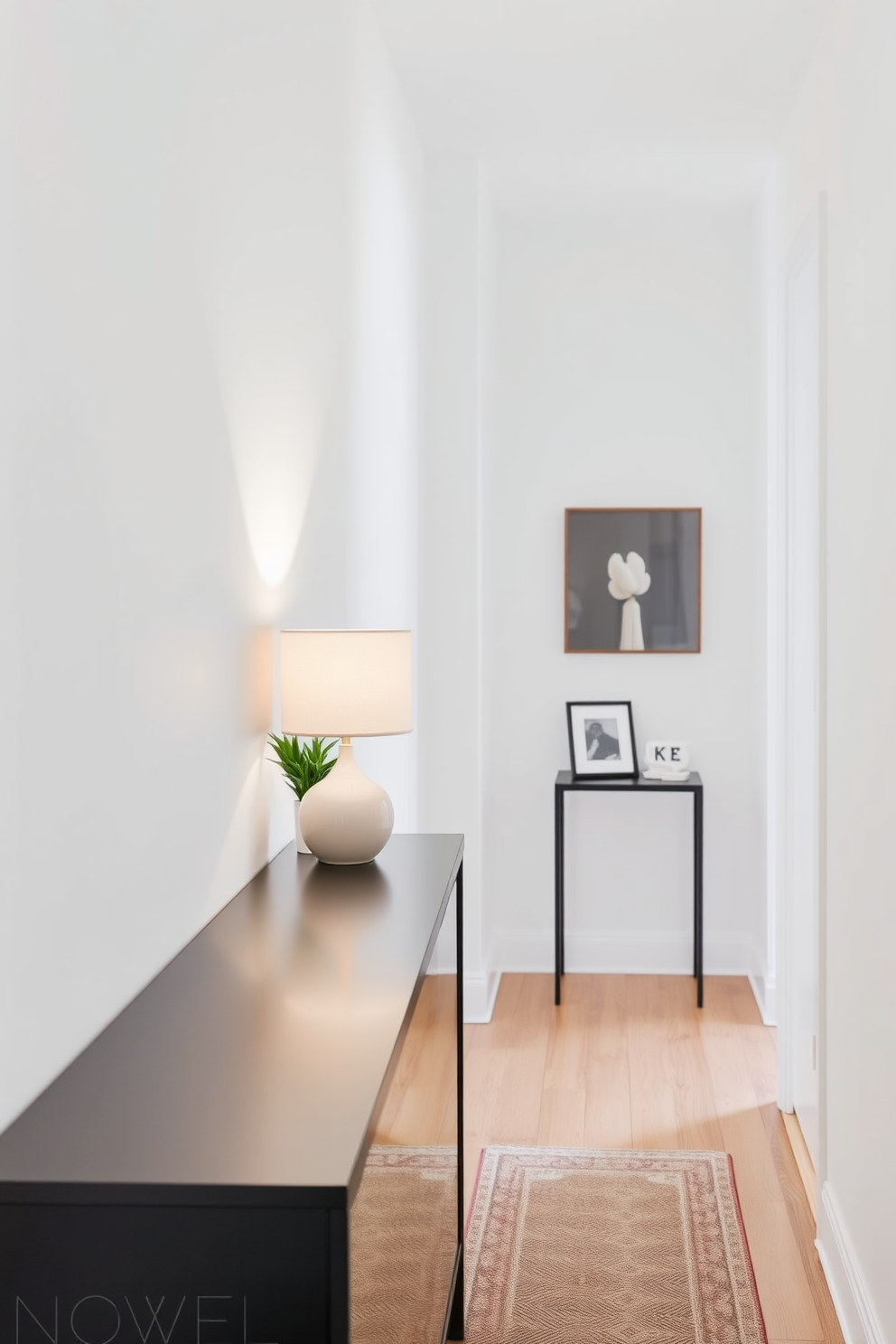 A small table lamp designed for soft lighting sits atop a sleek console table in the narrow foyer. The lamp features a delicate ceramic base with a soft fabric shade that diffuses light gently, creating a warm and inviting atmosphere. The foyer is adorned with a narrow console table against the wall, topped with decorative items like a small plant and a framed photo. The walls are painted in a light neutral color, enhancing the sense of space while a stylish runner rug adds texture and warmth to the floor.