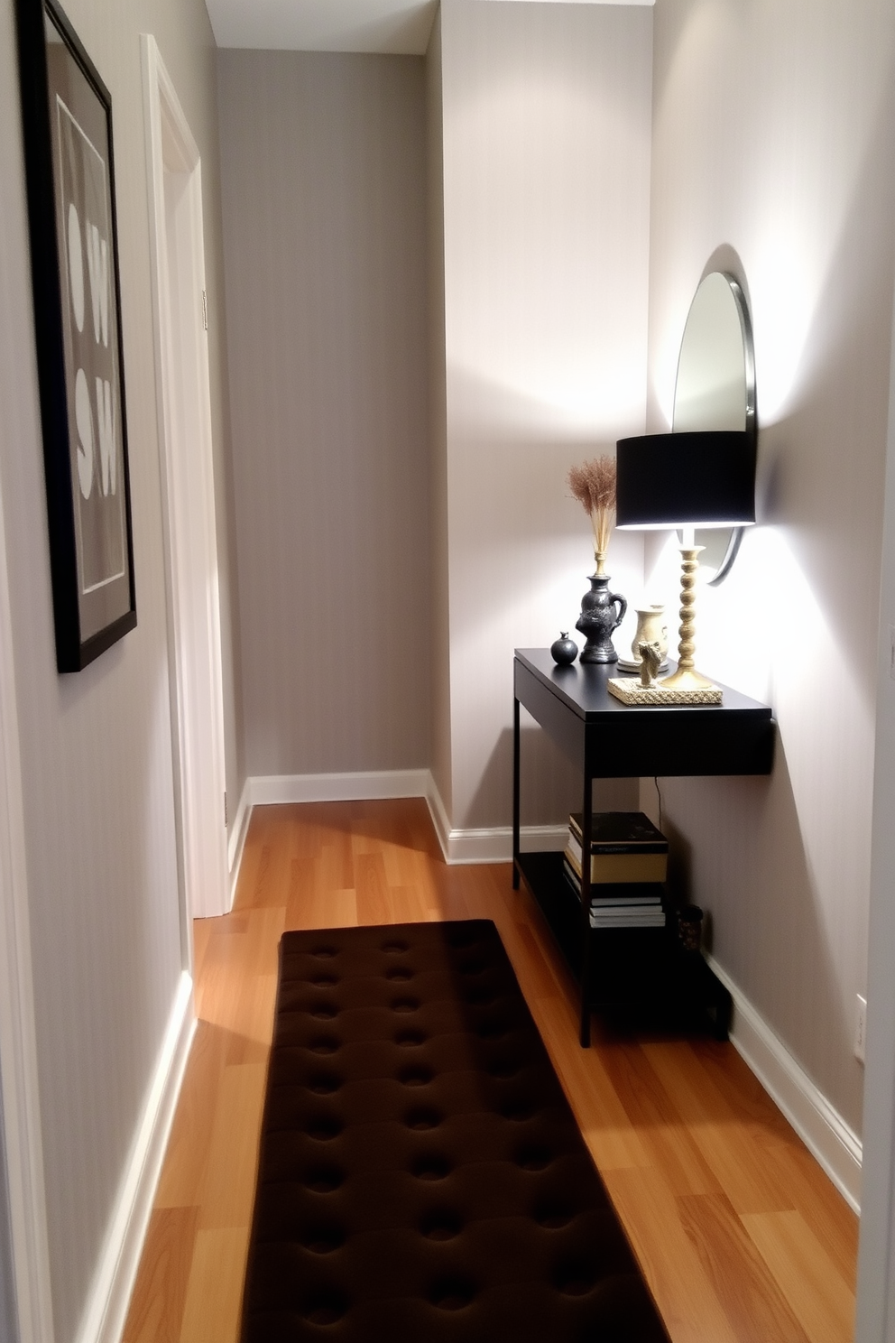 A narrow foyer featuring a cushioned floor mat that adds comfort and warmth to the space. The walls are adorned with subtle wallpaper, and a sleek console table sits against one side, topped with decorative items and a stylish lamp.