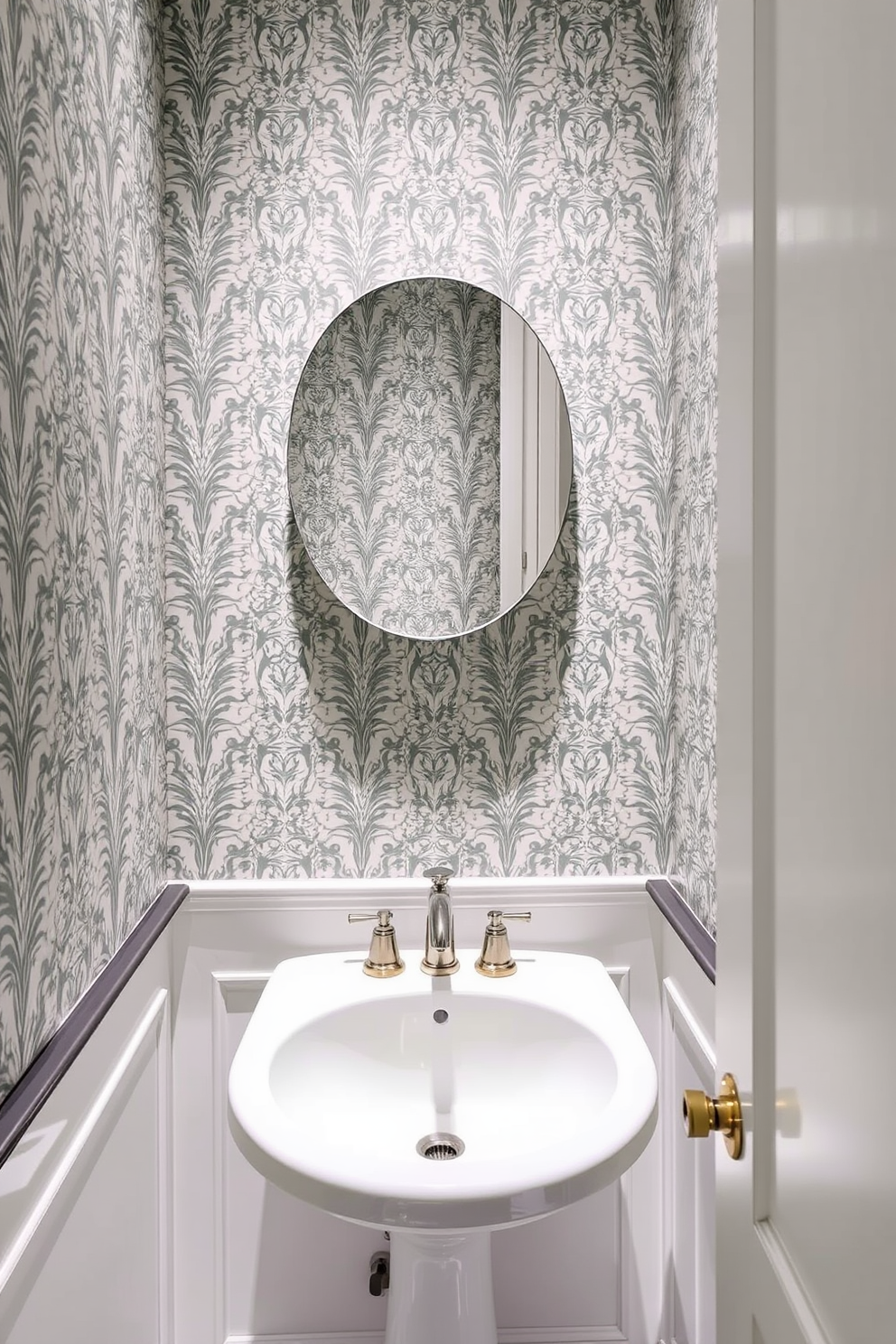 A narrow powder room adorned with patterned wallpaper that adds visual interest to the space. The design features a sleek pedestal sink with a vintage-style faucet and a small round mirror above it, reflecting the elegant wallpaper.