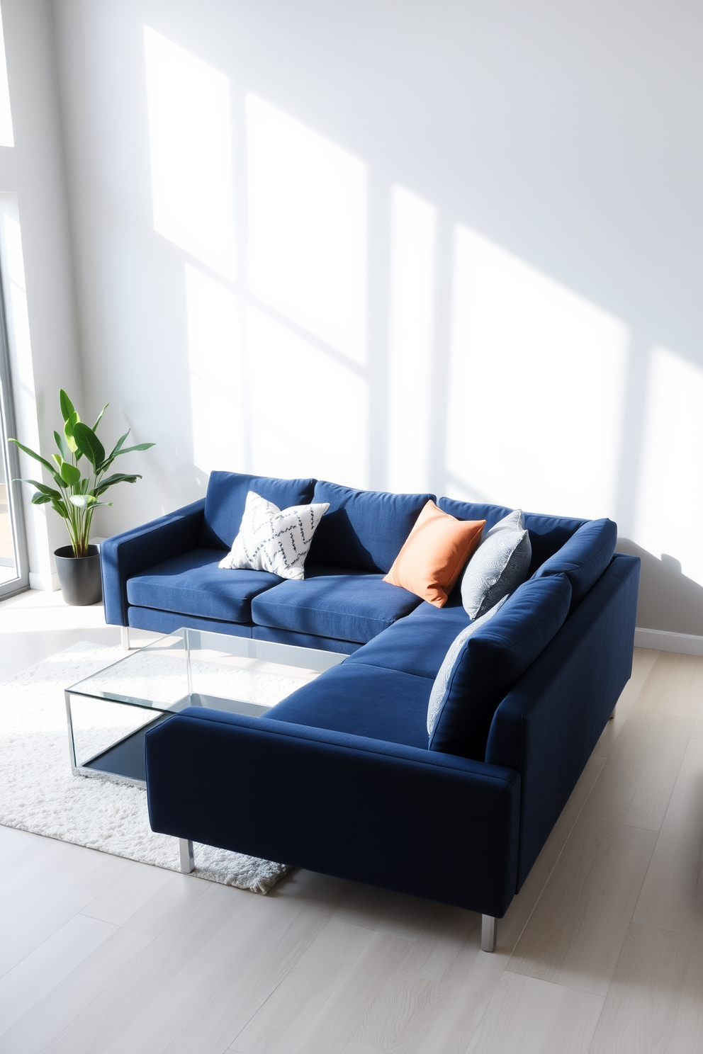 A modern minimalist living room features a navy blue couch positioned against a light gray wall. The floor is adorned with a soft white area rug, and a sleek glass coffee table sits in front of the couch. Large windows allow natural light to flood the space, highlighting the clean lines and simplicity of the decor. A few carefully selected decorative pillows in complementary colors are arranged on the couch for added comfort and style.