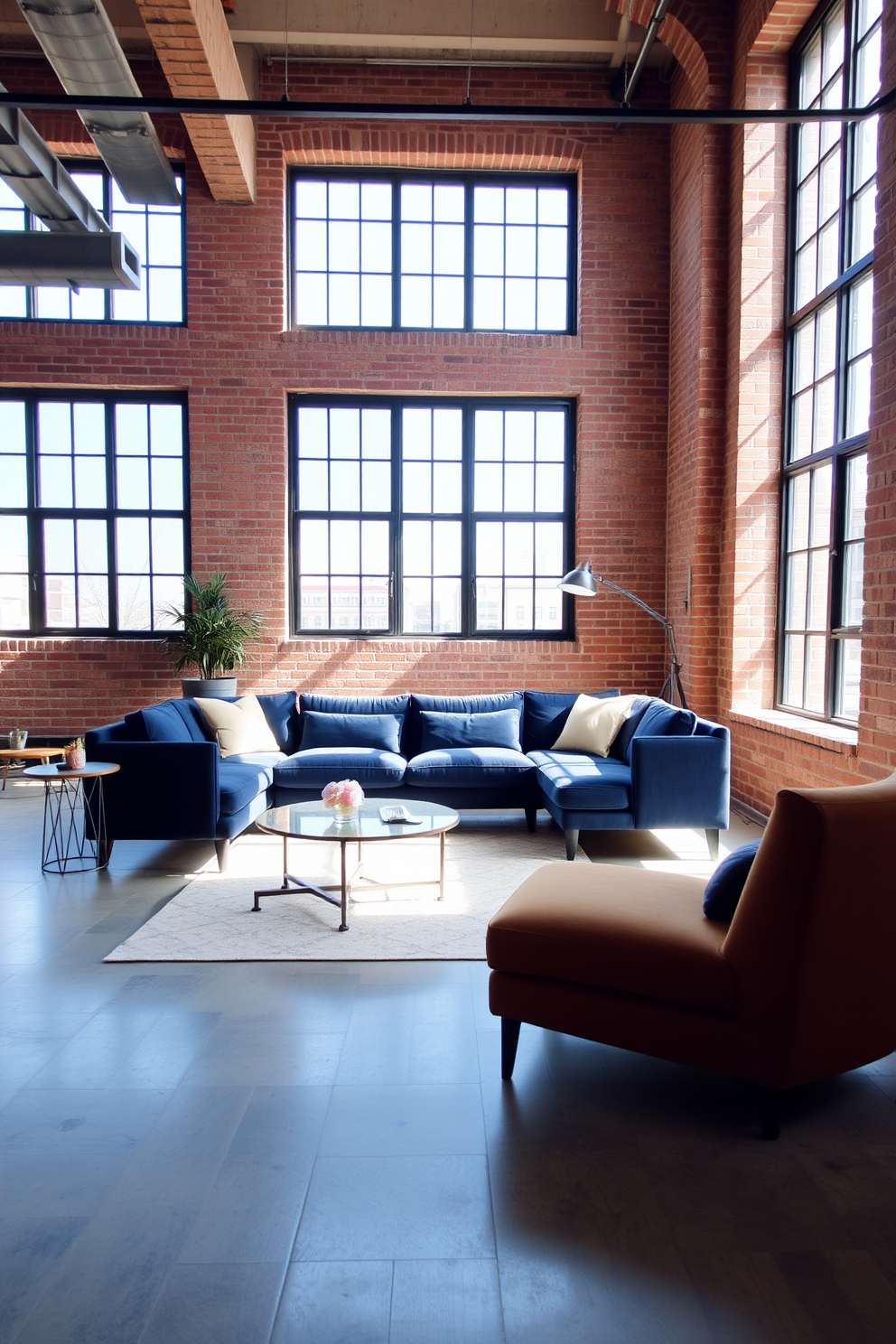 Chic navy sofa in an urban loft design. The space features exposed brick walls and large industrial windows that allow natural light to flood in.