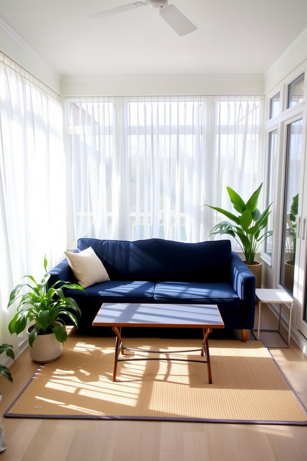 A bright sunroom filled with natural light features a navy blue sofa as the focal point. Surrounding the sofa are large windows adorned with sheer white curtains, allowing sunlight to filter in softly. The floor is covered with a light-colored area rug that complements the navy blue of the couch. Potted plants in the corners add a touch of greenery, enhancing the inviting atmosphere of the space.