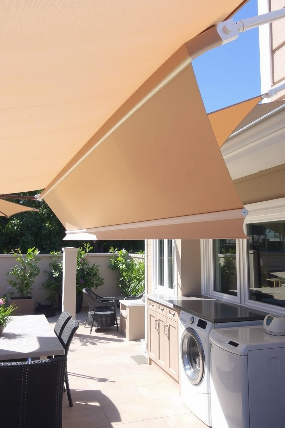 A retractable awning extends over a spacious patio area, providing ample shade during sunny days. The fabric is a soft beige color that complements the surrounding greenery and enhances the outdoor ambiance. The outdoor laundry room features a sleek design with built-in cabinetry and a countertop for folding clothes. Bright, natural light floods the space through large windows, creating a cheerful and functional environment for laundry tasks.