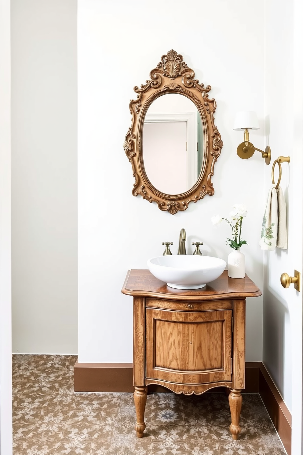 A charming powder room featuring cement tiles that add a rustic touch to the overall design. The walls are painted in a soft white hue, complementing the intricate patterns of the floor tiles. A vintage wooden washstand holds a round vessel sink with a brushed gold faucet. Above the sink, a decorative mirror with an ornate frame enhances the room's character and warmth.