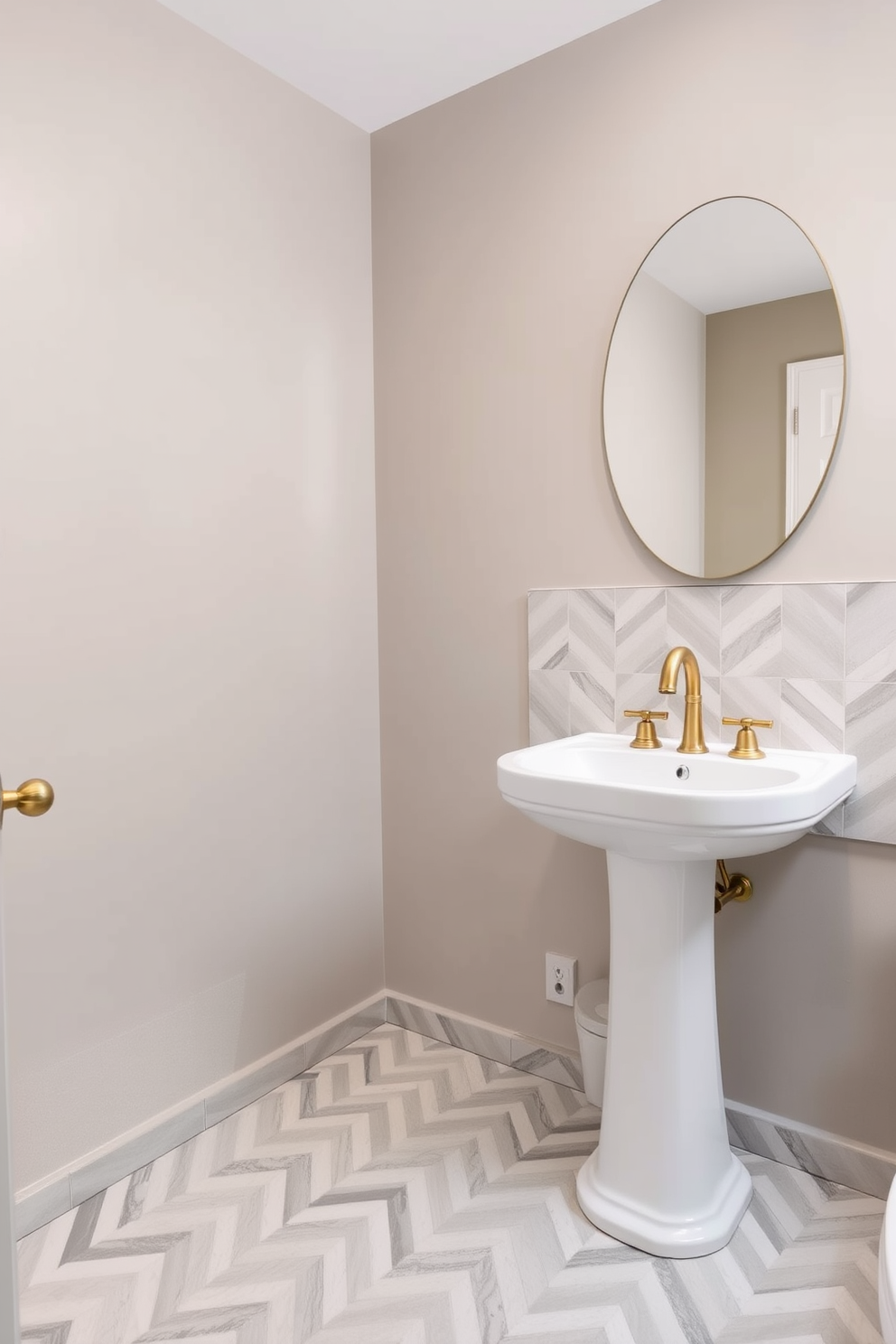 A stylish powder room features a striking chevron pattern tile that adds a dynamic touch to the space. The tiles are in a mix of soft gray and white tones, creating a modern yet inviting atmosphere. The walls are painted in a complementary light taupe, enhancing the overall elegance of the room. A sleek pedestal sink sits against the wall, adorned with a chic gold faucet that echoes the contemporary design.