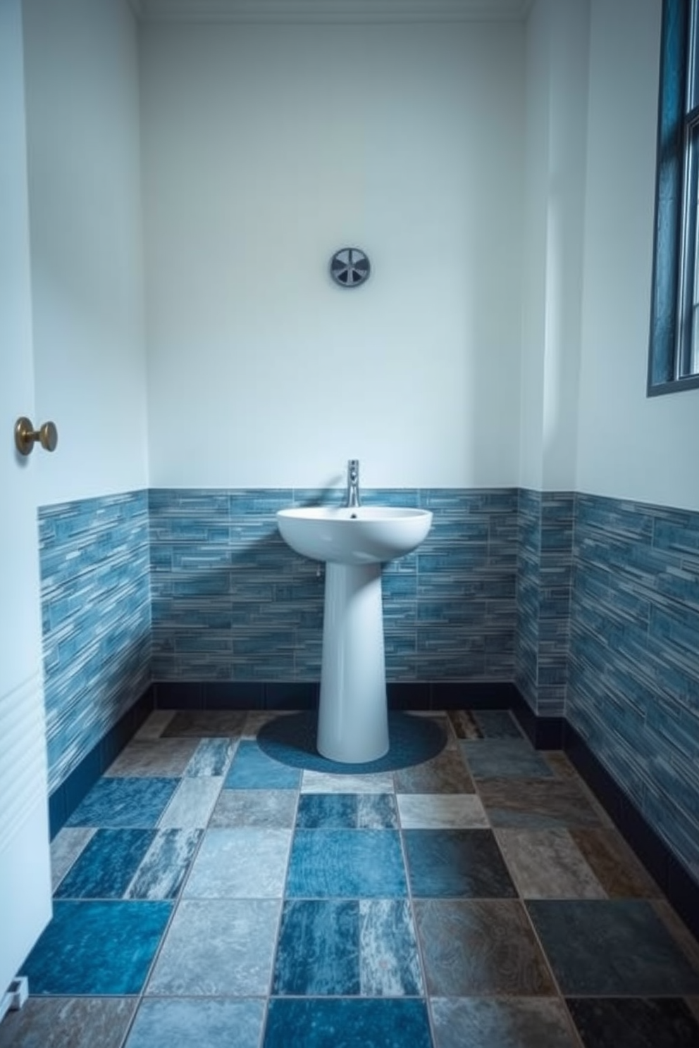 A powder room featuring tactile tiles that enhance the sensory experience. The floor is adorned with a mix of textured tiles in varying shades of blue and gray, creating a visually striking pattern. The walls are painted in a soft white to contrast the rich colors of the floor. A sleek pedestal sink sits centered in the room, complemented by a stylish wall-mounted faucet.