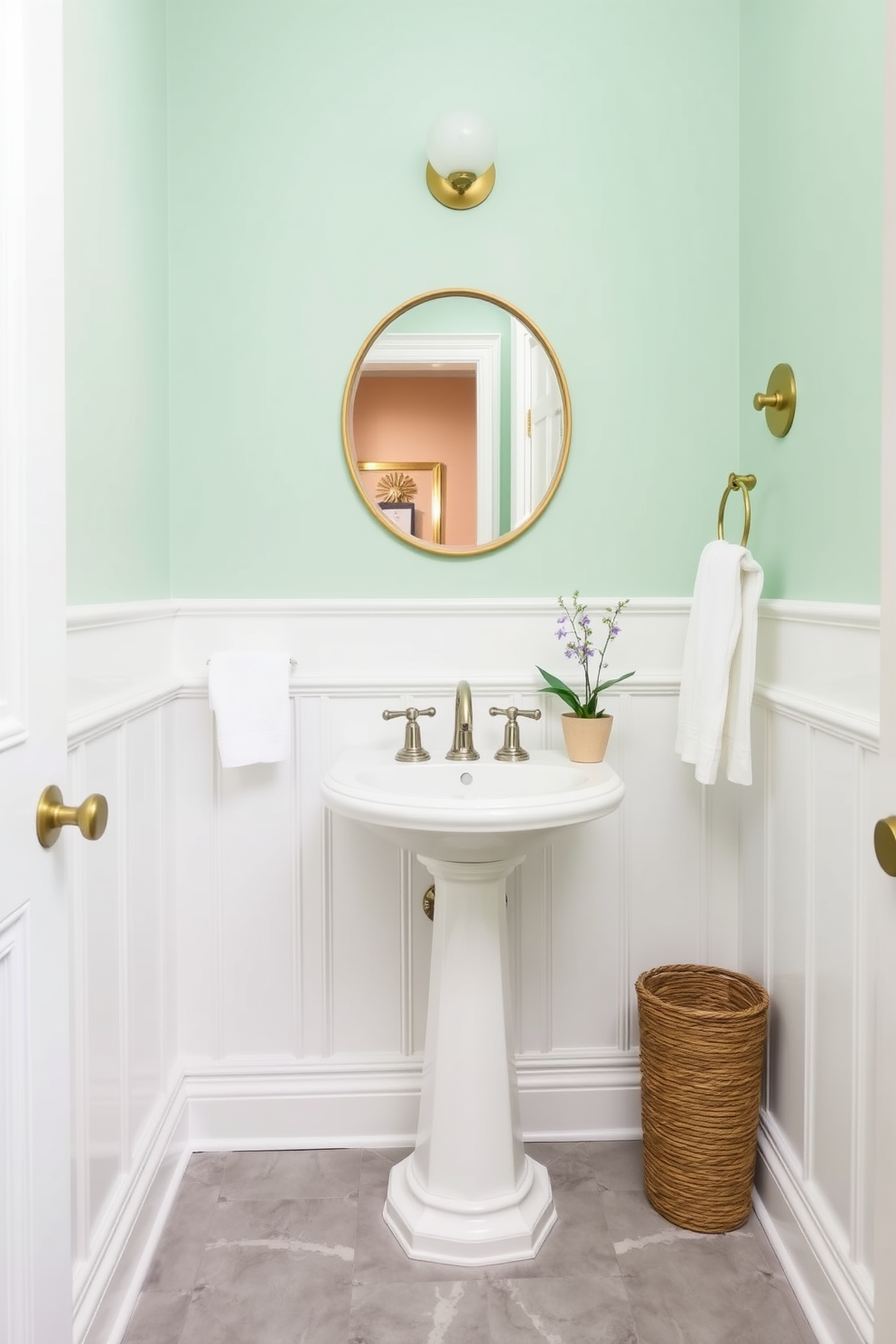 A light mint green powder room creates a fresh and inviting atmosphere. The walls are painted in a soft mint green, complemented by white wainscoting for a classic touch. Elegant fixtures, such as a sleek pedestal sink and a stylish wall-mounted faucet, enhance the room's charm. A round mirror with a delicate gold frame hangs above the sink, reflecting the light and adding a touch of sophistication. Accessorize with soft white towels and a small potted plant for a pop of natural color. The flooring features light gray tiles that provide a modern contrast to the mint green walls.