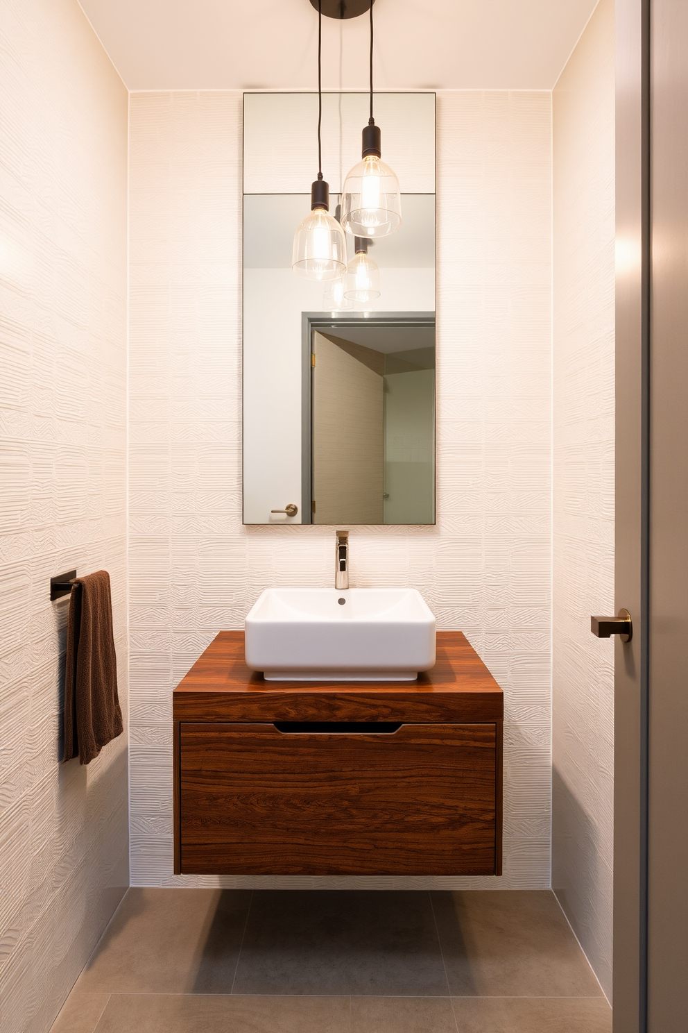 A chic powder room featuring a square sink with clean, geometric lines that complement the minimalist aesthetic. The walls are adorned with sleek, textured tiles in a soft neutral tone, enhancing the modern design. A floating vanity beneath the sink showcases a rich wood finish, providing a striking contrast to the light-colored walls. Elegant pendant lighting hangs above, casting a warm glow that accentuates the contemporary features of the space.