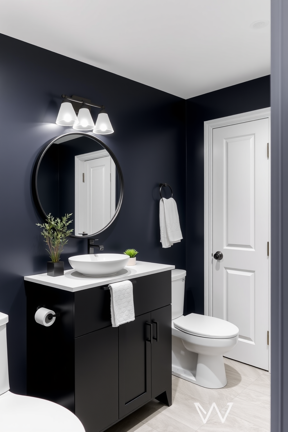 A stylish quarter bathroom featuring a striking contrast between dark navy walls and crisp white fixtures. The sleek black vanity is topped with a bright white sink, and a large round mirror with a black frame reflects the elegant lighting above. The floor is adorned with light grey tiles that complement the dark cabinetry, creating a balanced aesthetic. A small potted plant sits on the countertop, adding a touch of greenery to the modern design.