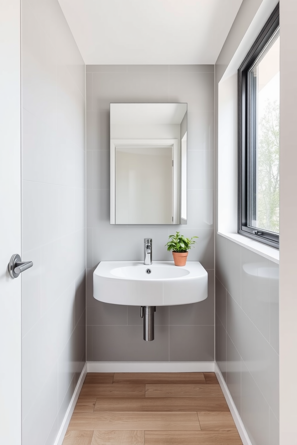 A compact corner sink is elegantly integrated into a modern bathroom design. The walls are adorned with soft gray tiles, while a sleek mirror above the sink reflects the natural light streaming in from a nearby window. The floor features light wood planks that add warmth to the space. A small potted plant sits on the sink's edge, bringing a touch of greenery to the minimalist aesthetic.