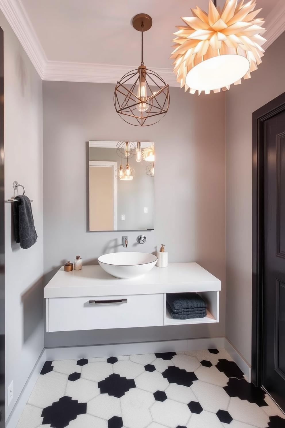 A stylish quarter bathroom featuring unique light fixtures as focal points. The walls are painted in a soft gray, with a contemporary floating vanity showcasing a sleek vessel sink. Above the sink, an artistic pendant light adds an element of surprise and sophistication. The floor is adorned with hexagonal tiles in a contrasting black and white pattern, enhancing the modern aesthetic.