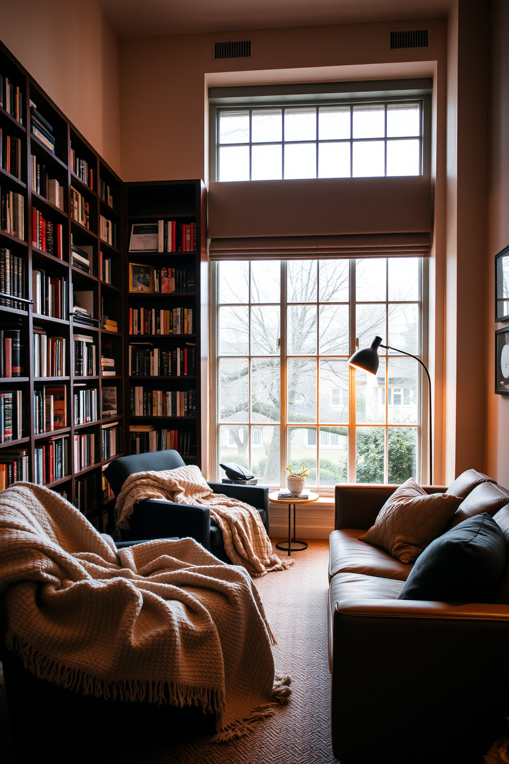 Cozy blankets are casually draped over a plush armchair and a sleek modern sofa, inviting relaxation and warmth. Soft ambient lighting illuminates the space, enhancing the inviting atmosphere of the reading room. Bookshelves filled with an eclectic mix of novels and decorative items line the walls, creating an intimate home library feel. A large window allows natural light to flood the room, highlighting a comfortable reading nook with a stylish floor lamp.