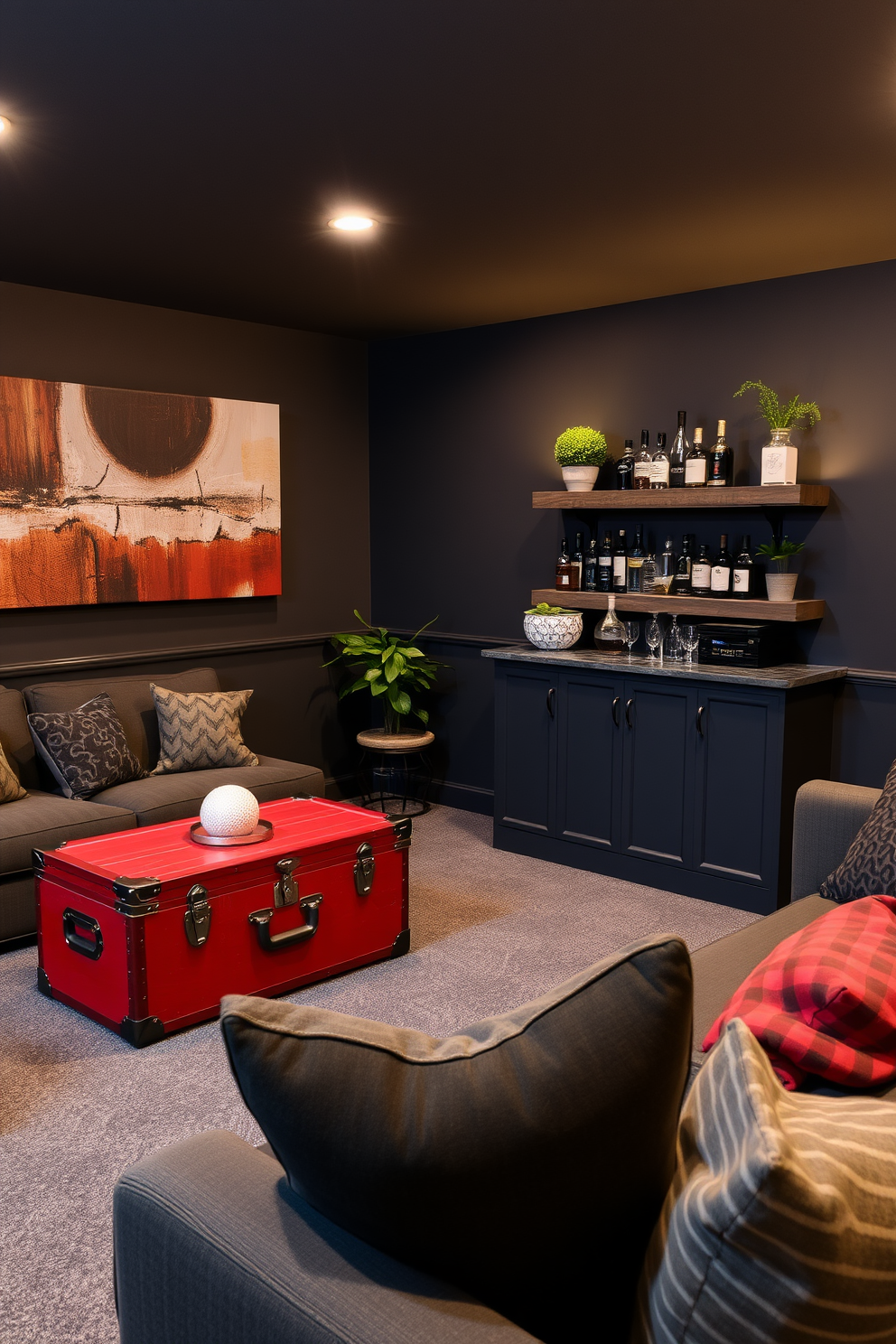 A cozy basement lounge featuring a red vintage trunk as a coffee table. The walls are painted in a deep charcoal gray, complemented by soft ambient lighting and plush seating arrangements. In one corner, a small bar area with rustic wooden shelves displays an array of spirits and glasses. Decorative elements include a large abstract painting above the couch and a few potted plants for a touch of greenery.