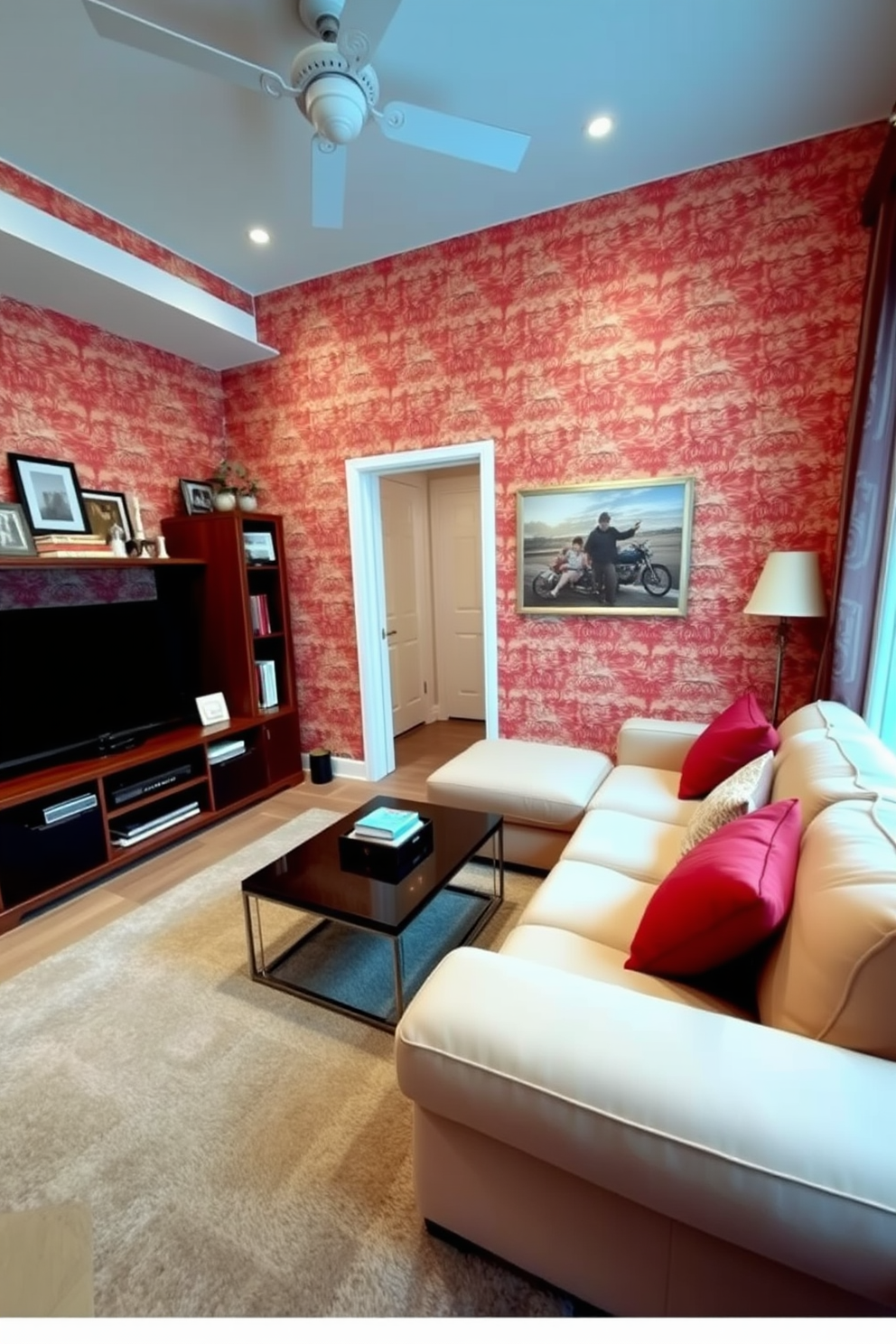 A cozy family room adorned with red and cream patterned wallpaper that adds warmth and character to the space. The room features a plush cream sectional sofa, accented with red throw pillows, and a stylish coffee table in the center. To the left, a modern entertainment unit holds a large flat-screen TV, surrounded by decorative shelving filled with books and family photos. A soft area rug in neutral tones anchors the seating area, providing comfort and inviting relaxation.