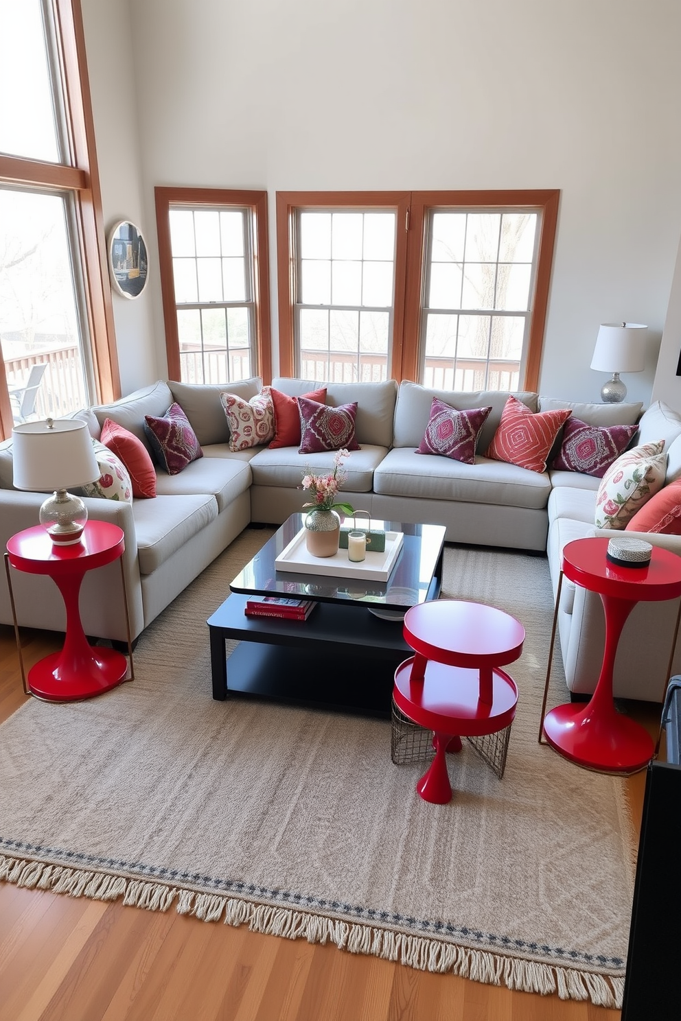 A cozy family room adorned with seasonal decor items featuring rich shades of red. Plush red throw pillows and a vibrant red area rug complement the warm wooden furniture and create an inviting atmosphere. The walls are decorated with seasonal artwork that highlights red tones, adding a festive touch. A large, comfortable sectional sofa is arranged around a central coffee table, adorned with red-themed decorative accents and candles.