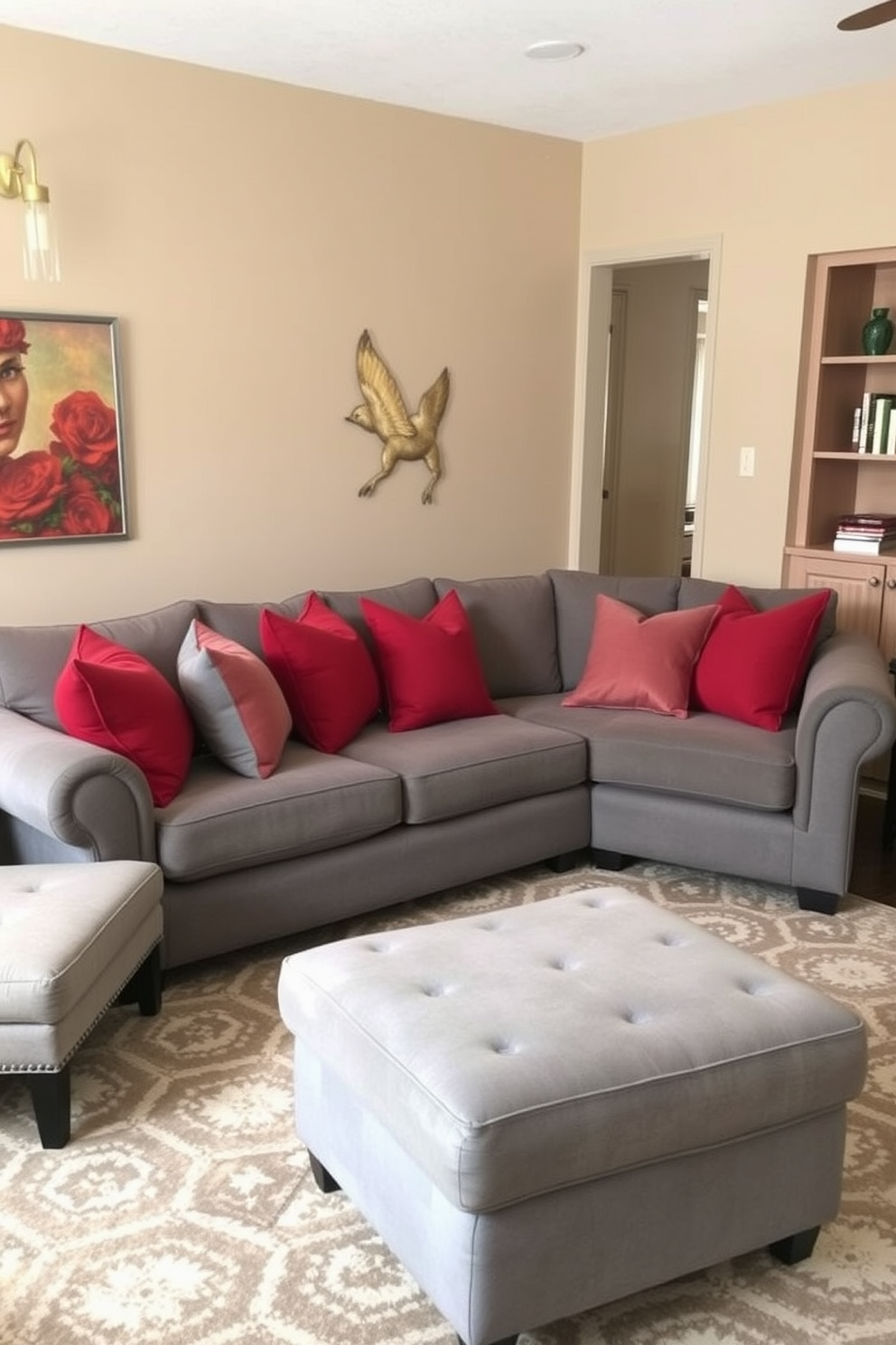 A cozy family room featuring a plush gray sofa adorned with layered red and gray throw pillows. The walls are painted in a warm beige tone, and a large area rug with geometric patterns anchors the seating area.