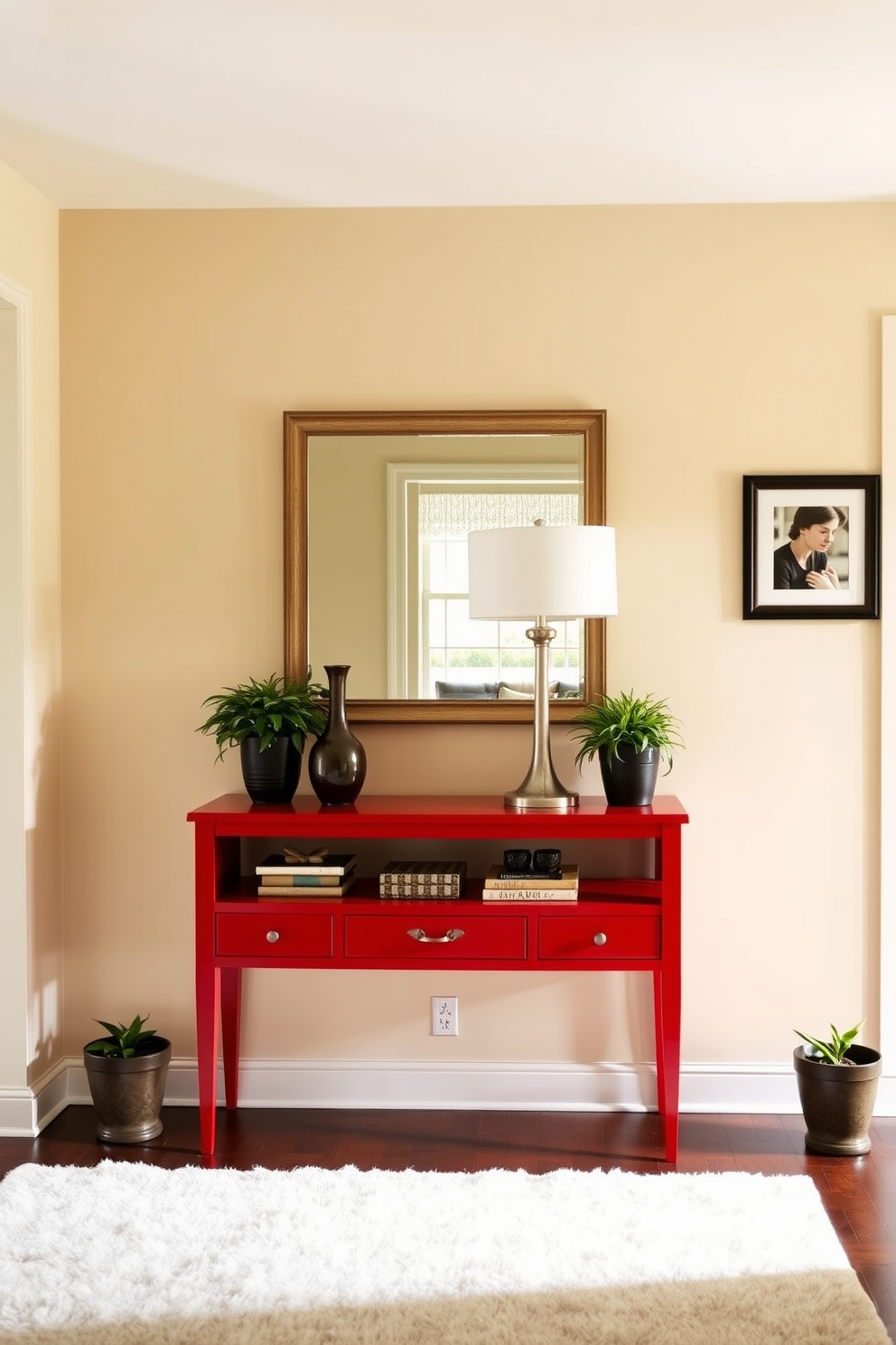 A bright red console table stands against the wall in the foyer, adorned with a collection of decorative items including a sleek vase and an elegant lamp. The walls are painted in a soft cream color, while a stylish mirror hangs above the console, reflecting the warm light that fills the space. The foyer features a plush area rug in neutral tones that complements the vibrant red of the console table. Potted plants are placed on either side of the table, adding a touch of greenery and life to the entrance.