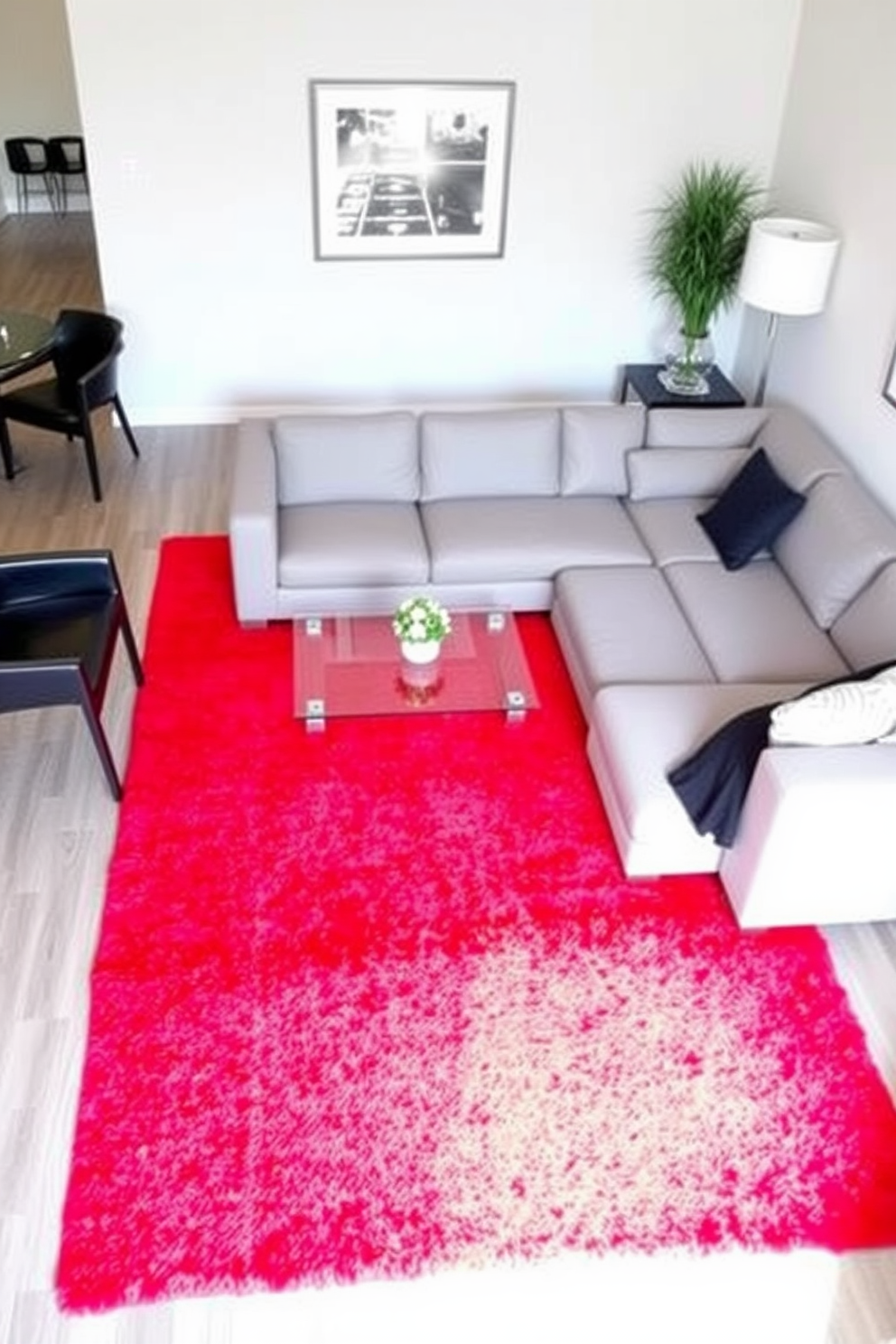 Bright red curtains enhance natural light in a spacious living room. The space features a plush white sofa adorned with colorful throw pillows and a sleek glass coffee table at the center. A large abstract painting with bold colors hangs on the wall, complementing the vibrant curtains. The room is illuminated by a modern chandelier that adds a touch of elegance to the overall design.