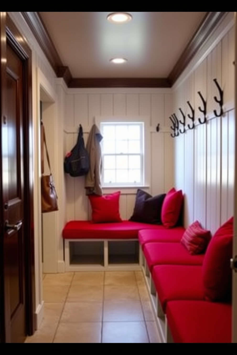 A striking entryway features a red sliding barn door that adds a pop of color and rustic charm. The door is complemented by a warm wood frame and a natural wood floor that enhances the inviting atmosphere. The mudroom showcases a red color scheme with functional design elements. Built-in storage benches and hooks are arranged along the walls, creating an organized and stylish space for coats and shoes.