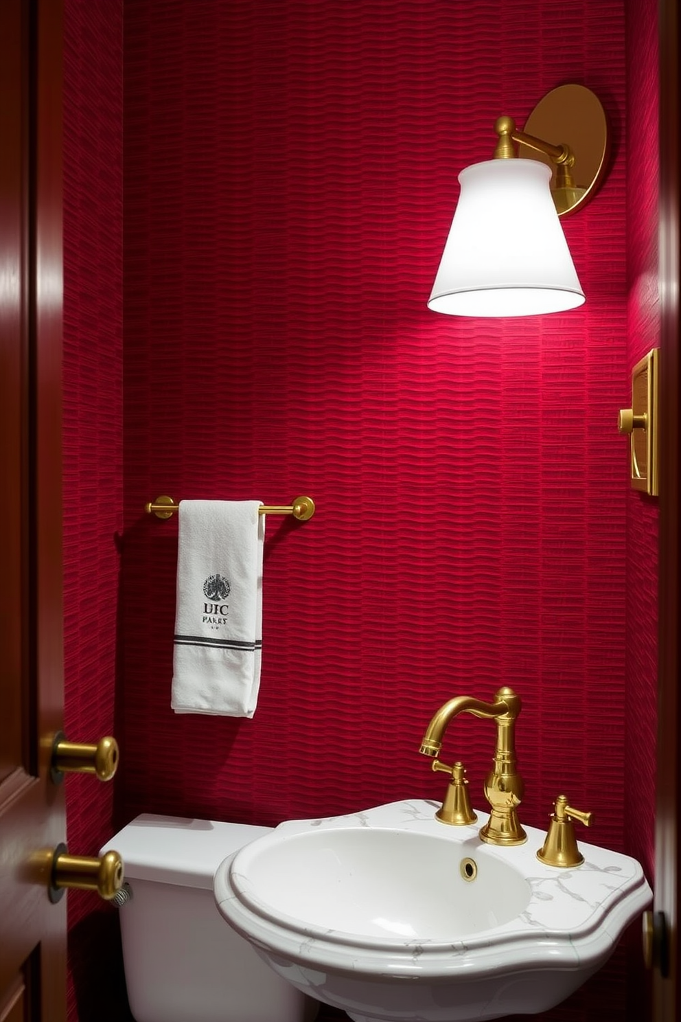 A luxurious powder room featuring a striking red and gold color combination. The walls are adorned with rich red wallpaper, while gold accents highlight the elegant fixtures and accessories throughout the space. A stylish pedestal sink with a gold faucet sits against the wall, complemented by a round gold-framed mirror above it. Plush red towels are neatly displayed, adding a touch of warmth and sophistication to the overall design.