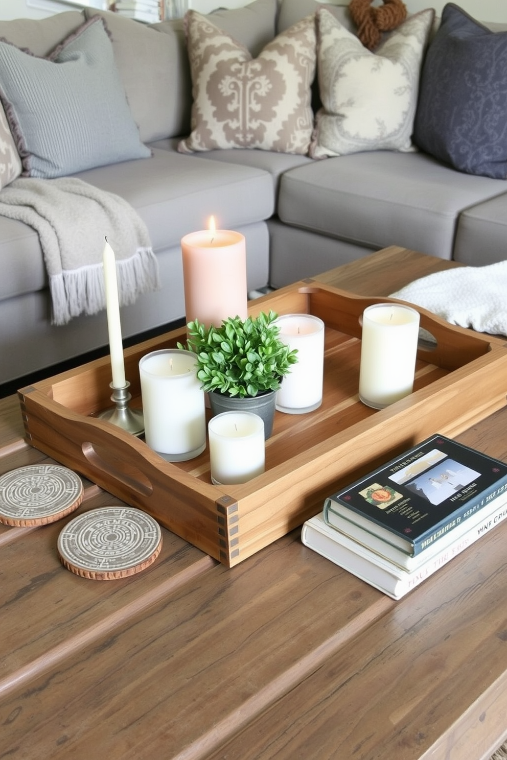 A farmhouse style coffee table centerpiece features a large wooden tray that holds a collection of seasonal candles and a small potted plant. Surrounding the centerpiece are textured coasters and a stack of vintage books, adding warmth and charm to the rustic living room design.