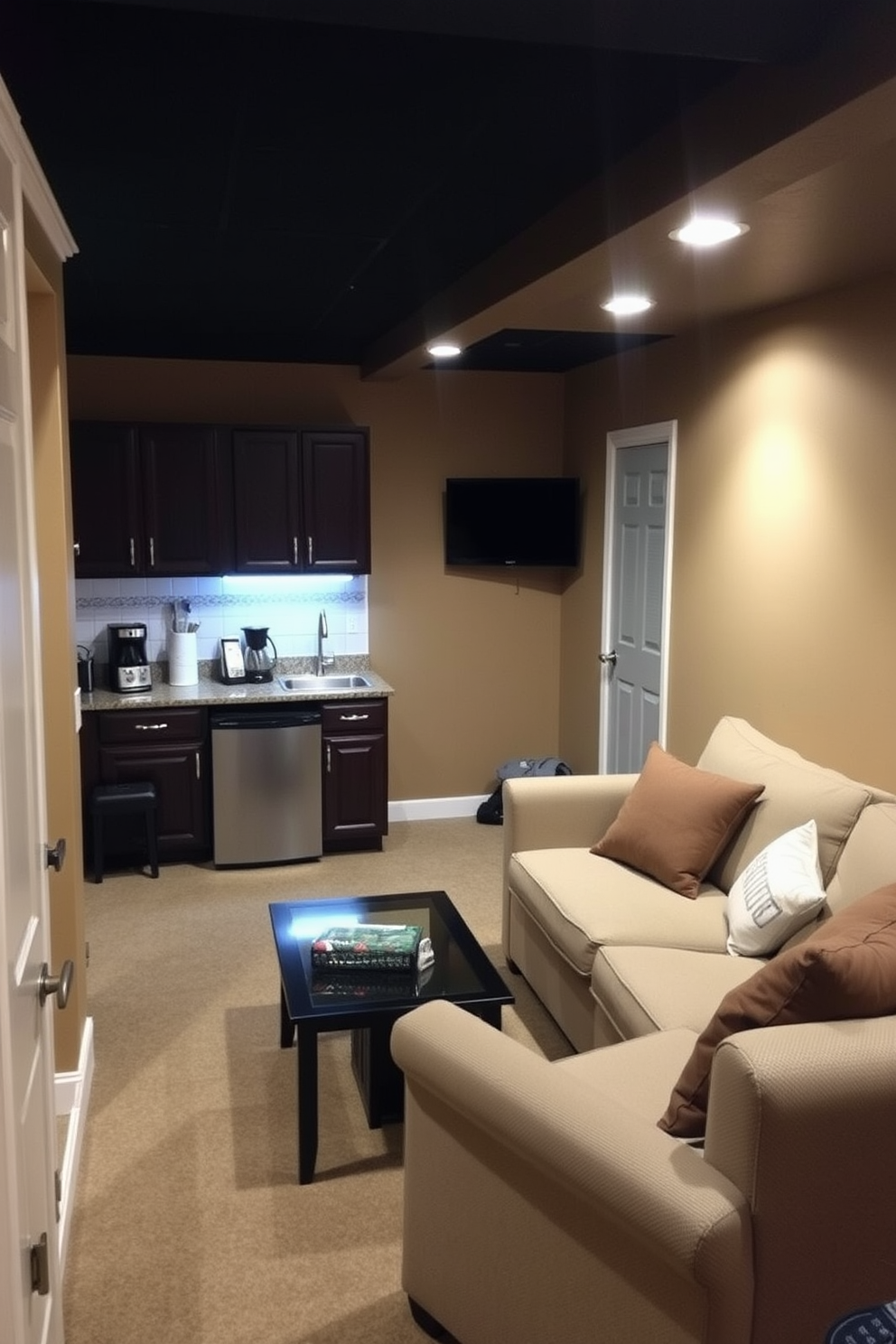 A cozy basement space designed for relaxation and entertainment. The area features a small kitchenette with a compact refrigerator, a sink, and a countertop for meal prep. The walls are painted in a warm neutral tone, creating an inviting atmosphere. Comfortable seating is arranged around a coffee table, with soft lighting enhancing the overall ambiance.