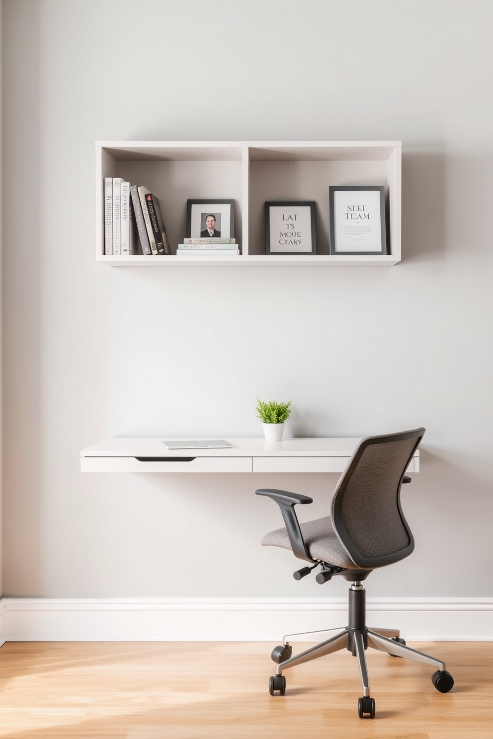 A wall-mounted desk is elegantly positioned against a light gray wall, creating a minimalist workspace that maximizes floor space. The desk features a sleek design with clean lines, complemented by a comfortable ergonomic chair in a soft fabric. Above the desk, open shelving displays neatly arranged books and decorative items, adding a personal touch to the office. A small potted plant sits on the desk, bringing a hint of greenery to the serene and organized environment.