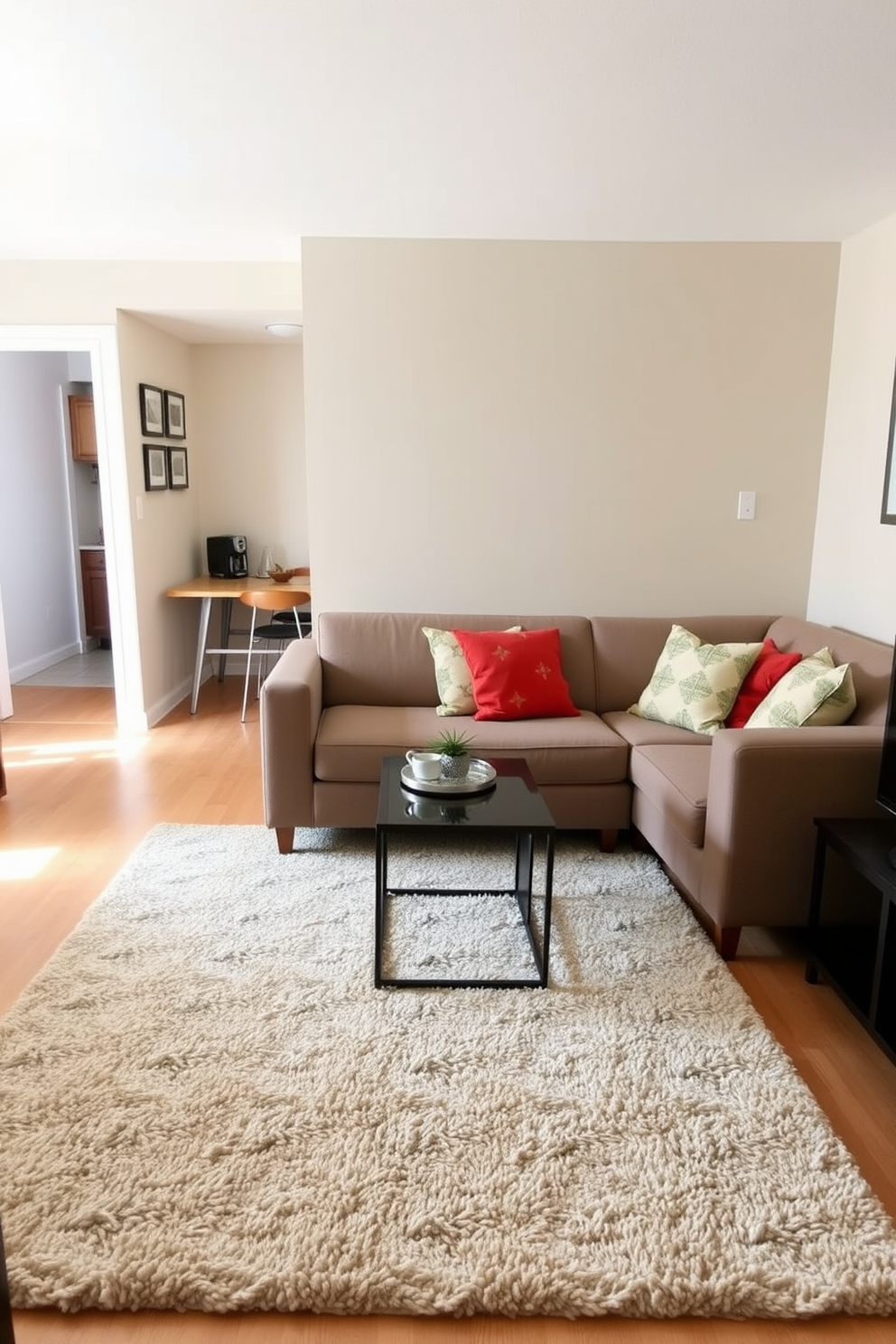 A cozy living area is defined by a plush area rug that anchors the seating arrangement. The rug features a subtle geometric pattern that complements the warm color palette of the room. In the small one-bedroom apartment, the living space seamlessly transitions into the kitchen area. A compact sofa, adorned with colorful throw pillows, invites relaxation while maximizing the limited space.