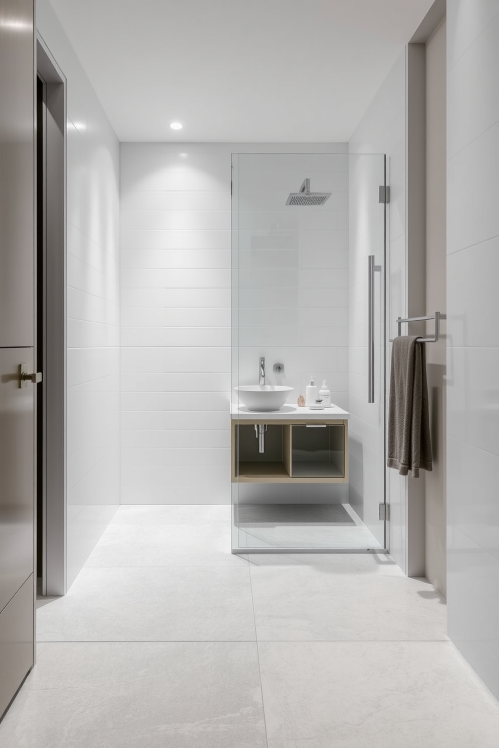 A small bathroom featuring large format tiles that create an illusion of spaciousness. The walls are adorned with sleek white tiles and the floor is covered with oversized gray tiles to enhance the open feel. A minimalist shower area showcases a frameless glass enclosure with a rainfall showerhead. A compact vanity with a vessel sink sits against the wall, complemented by modern fixtures and soft ambient lighting.