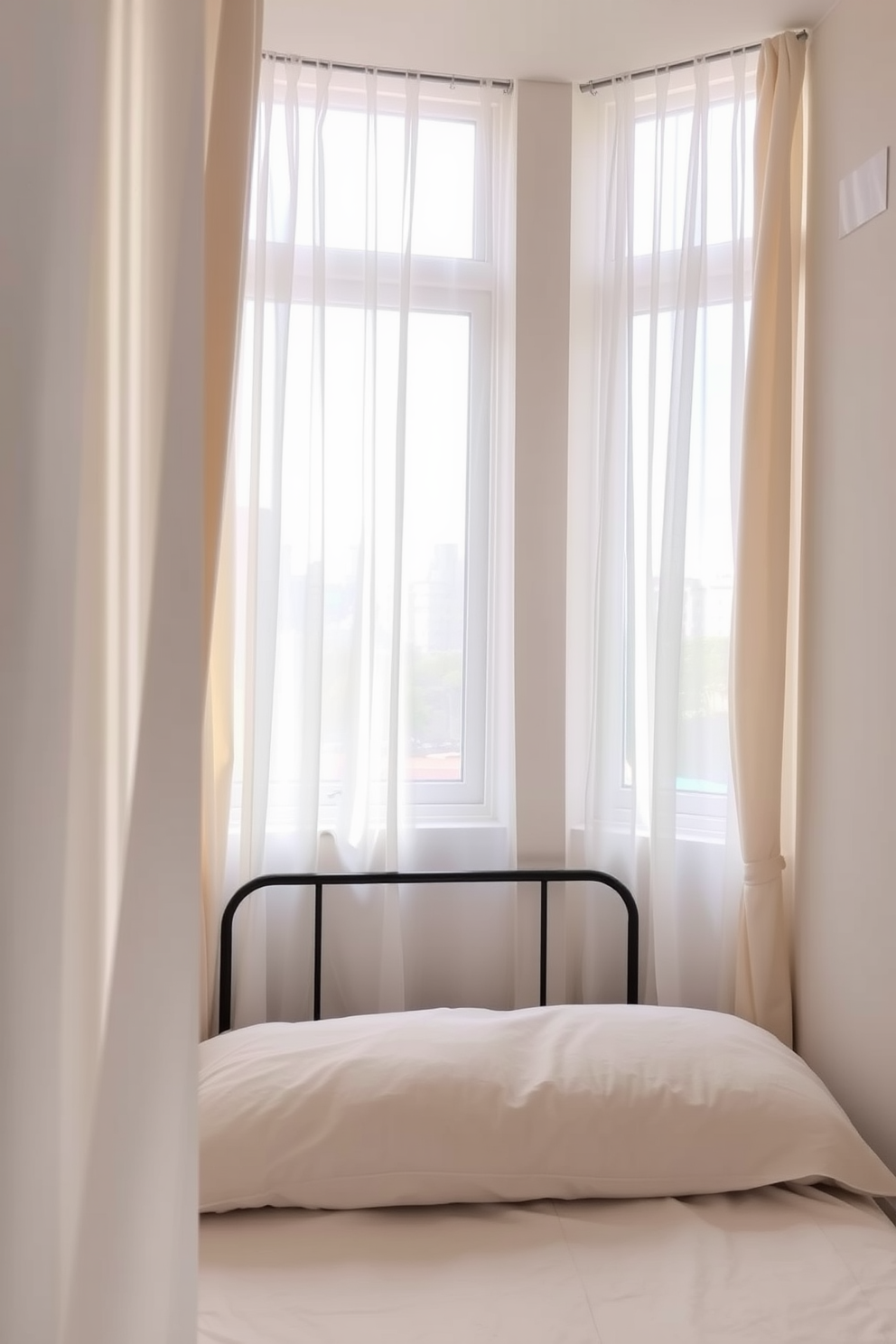 A cozy small bedroom with sheer curtains allowing natural light to filter softly through the windows. The walls are painted in a light pastel color, and the space features a compact bed with a stylish headboard and minimalistic bedding.