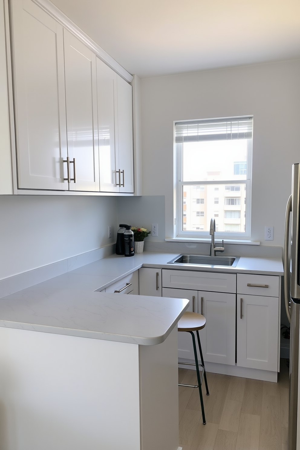 A small condo kitchen with a modern aesthetic featuring corner cabinets for efficient storage. The cabinetry is a sleek white with brushed nickel handles, and the countertops are a light gray quartz with subtle veining. The kitchen includes a compact island with bar seating, perfect for casual dining. Natural light floods the space through a large window above the sink, enhancing the airy feel of the room.