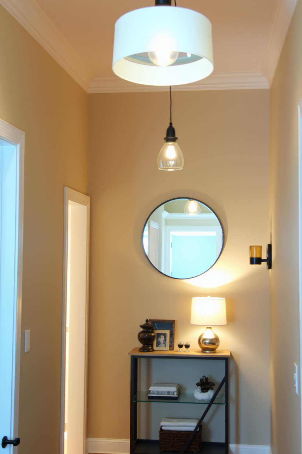 Layered lighting creates a warm and inviting atmosphere in a small entryway. Soft pendant lights hang from the ceiling, complemented by wall sconces that provide additional illumination along the walls. The entryway features a narrow console table against one wall, topped with decorative items and a small lamp. A round mirror above the table reflects the light, making the space feel larger and more welcoming.