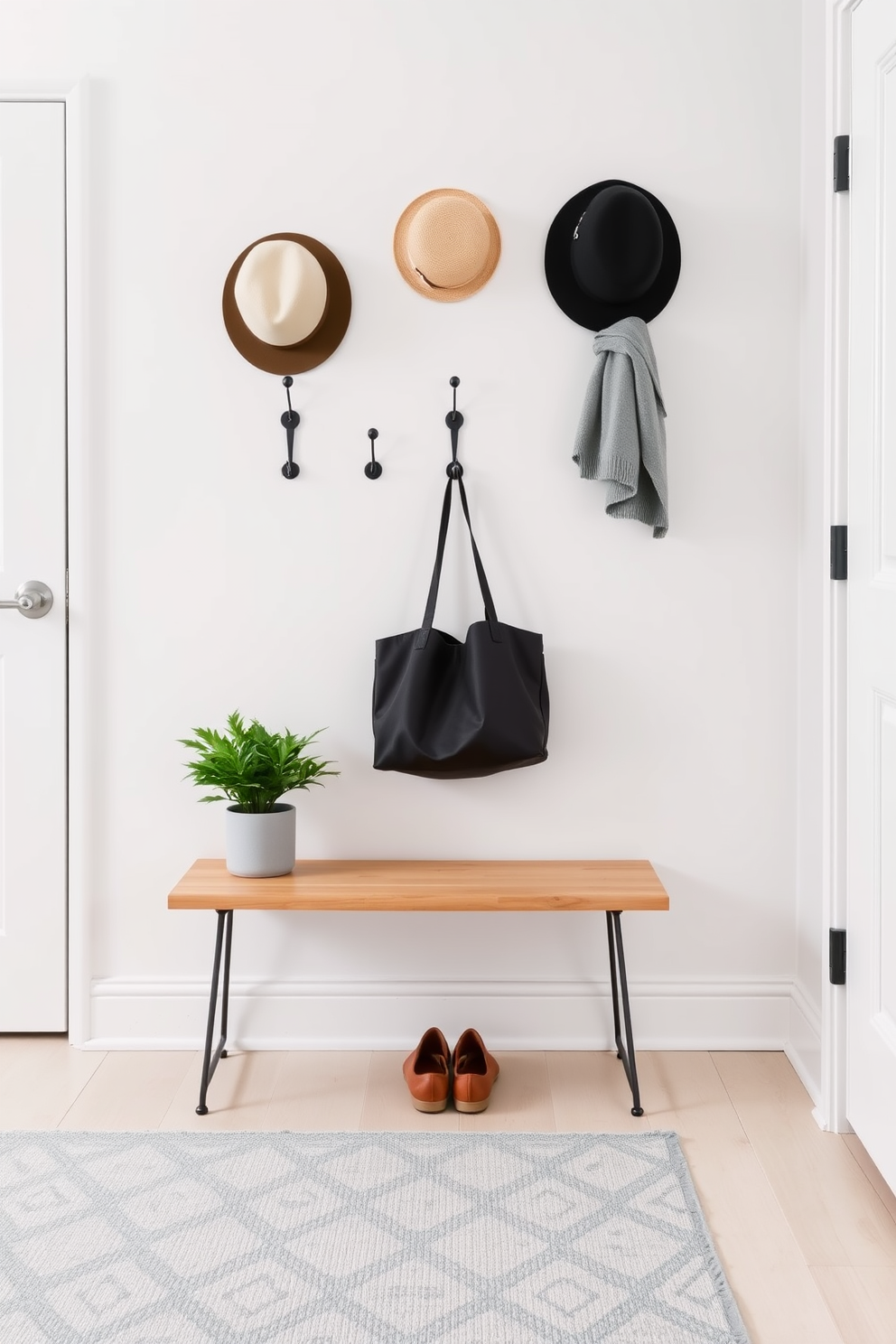 Chic hooks for hats and bags are mounted on a clean white wall, providing a stylish yet functional solution for a small entryway. The floor is adorned with a light gray rug that complements the soft pastel color scheme of the space. A minimalist bench with a natural wood finish sits beneath the hooks, offering a place to sit while putting on shoes. A small potted plant adds a touch of greenery, enhancing the inviting atmosphere of the entryway.