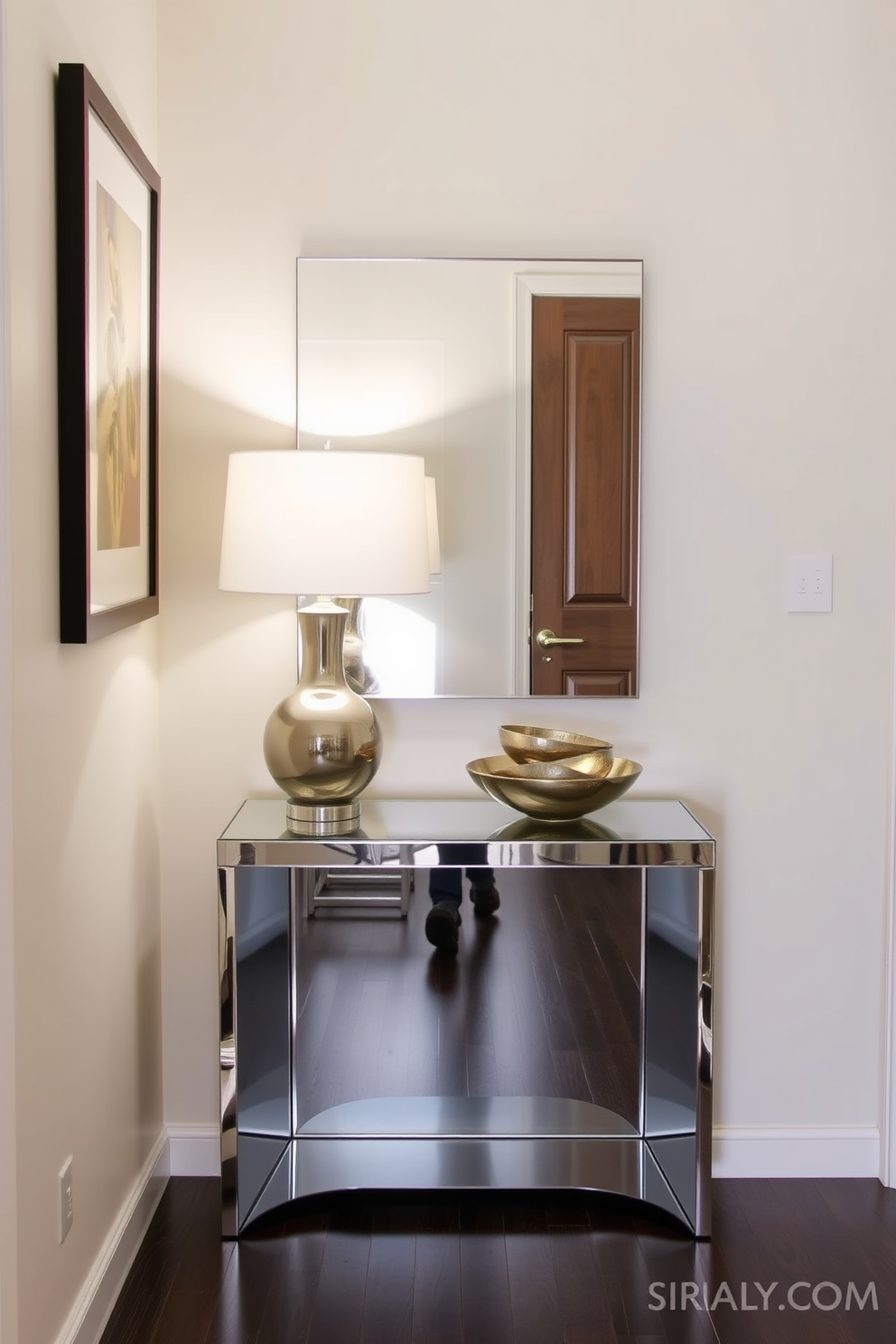 A small entryway features a sleek mirrored console table that reflects light and creates an illusion of space. The table is adorned with a stylish lamp and a decorative bowl, enhancing the welcoming atmosphere of the area.