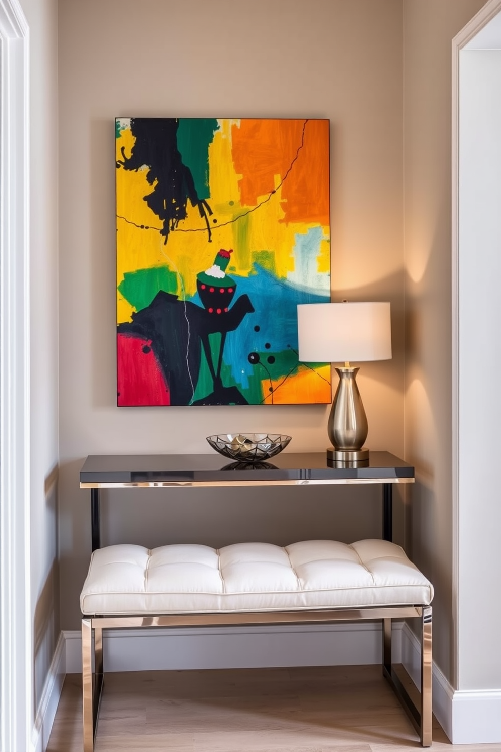 A small entryway features a vibrant piece of abstract wall art that draws the eye and adds a pop of color to the space. A sleek console table with a polished finish sits against the wall, topped with a stylish lamp and a decorative bowl for keys. The walls are painted in a soft neutral tone to create a welcoming atmosphere. A small bench with plush cushions provides a comfortable spot for putting on shoes, enhancing both functionality and style.