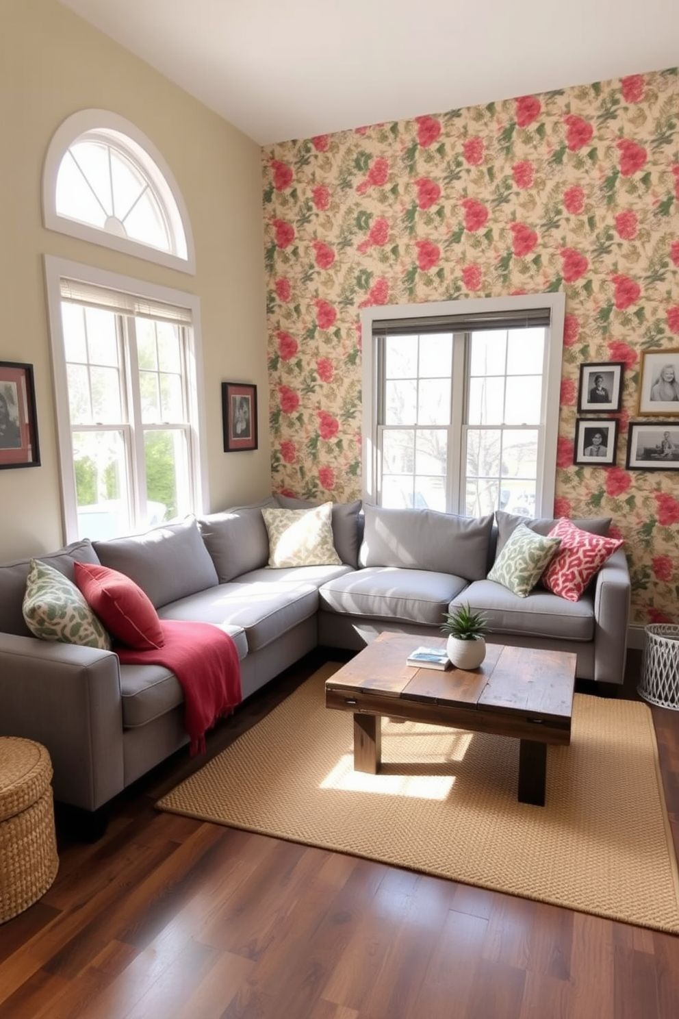 A cozy small family room featuring an accent wall adorned with vibrant wallpaper showcasing a floral pattern. The room includes a plush sectional sofa in a soft grey fabric, complemented by colorful throw pillows that add a pop of color. Natural light streams in through large windows, illuminating a stylish coffee table made of reclaimed wood placed at the center. A warm area rug anchors the seating area, while a few framed family photos adorn the walls, adding a personal touch to the space.