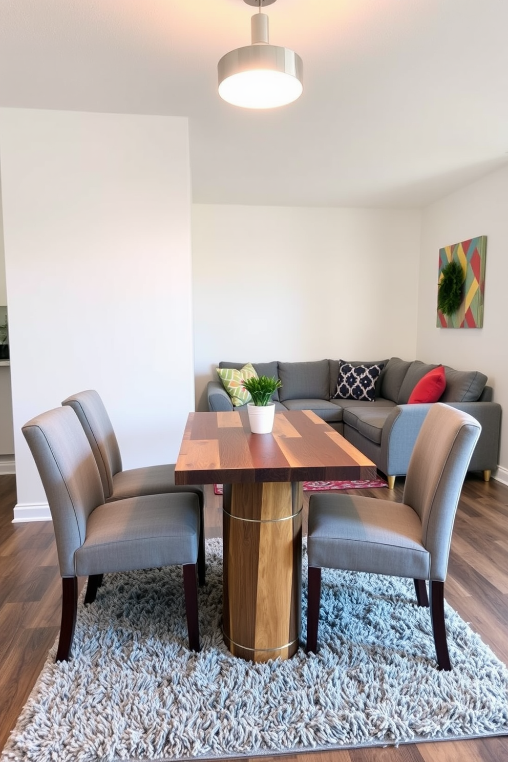 A compact dining table made of reclaimed wood is surrounded by four upholstered chairs in a soft gray fabric. Above the table, a modern pendant light with a warm glow creates an inviting atmosphere for family meals. In the small family room, a cozy sectional sofa is adorned with colorful throw pillows, providing ample seating. A sleek coffee table in the center complements a plush area rug that adds warmth to the space.