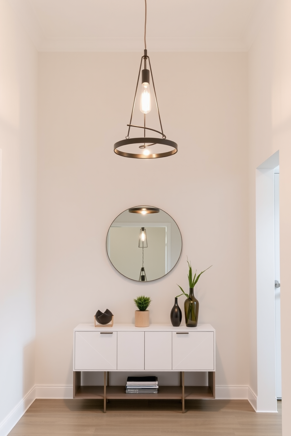 A stylish lighting fixture hangs gracefully from the ceiling, casting a warm glow throughout the space. The foyer features a sleek console table against the wall, adorned with decorative objects and a small potted plant. The walls are painted in a soft neutral tone, enhancing the sense of openness and light. A round mirror above the console reflects the light fixture, creating an inviting focal point in the entryway.