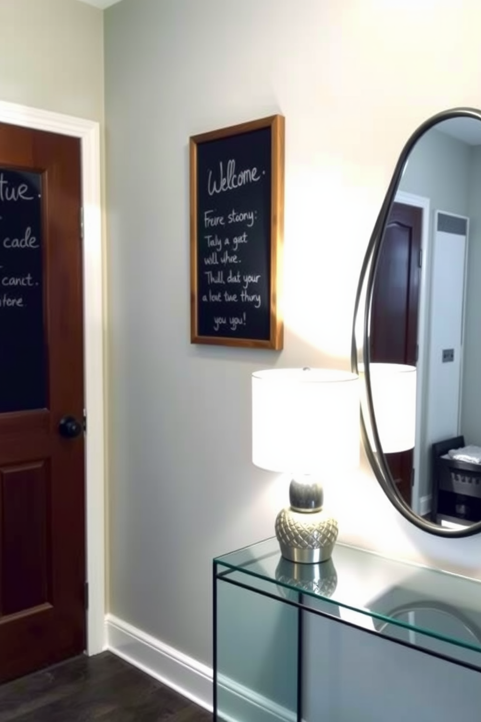 A small foyer with a welcoming atmosphere featuring a chalkboard mounted on the wall for messages. The space includes a sleek console table with a decorative lamp and a small potted plant, complemented by a stylish mirror above the table.