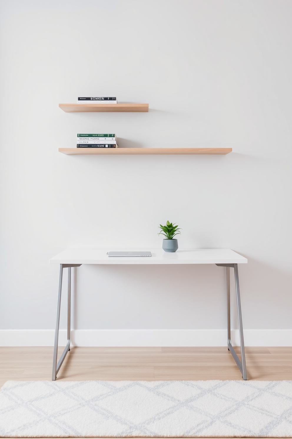 A minimalist desk is positioned against a light gray wall, featuring clean lines and a sleek design. Above the desk, floating shelves are mounted, showcasing a few carefully curated books and decorative items. The floor is covered with a soft area rug in neutral tones, adding warmth to the space. A small potted plant sits on the desk, bringing a touch of greenery to the minimalist aesthetic.