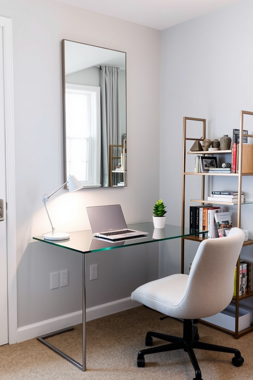 A cozy small home office featuring a sleek glass desk positioned against a light gray wall. On the desk, there is a minimalistic laptop and a stylish desk lamp, while a large mirror hangs above it, reflecting natural light from a nearby window. To the right of the desk, a compact shelving unit displays books and decorative items, adding personality to the space. A comfortable chair with soft upholstery invites productivity, and a small potted plant sits on the desk, bringing a touch of greenery indoors.