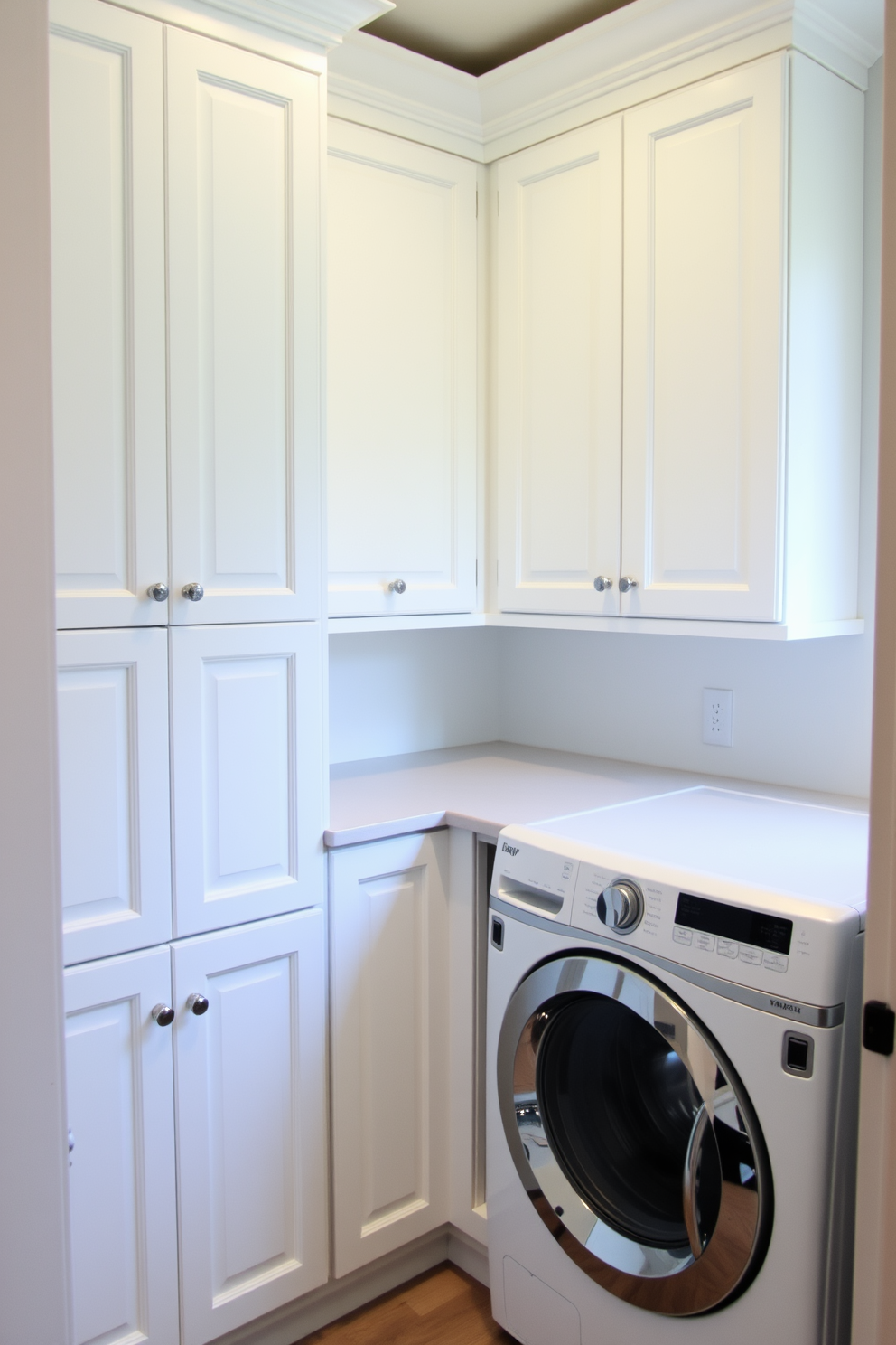 A small laundry room features built-in cabinetry designed for optimal storage and organization. The cabinetry is painted in a soft white finish, complementing the light gray walls and offering a clean, airy feel to the space. A stylish countertop runs above the cabinetry, providing a functional workspace for folding laundry. To the side, a compact washer and dryer are seamlessly integrated into the design, maximizing efficiency without sacrificing aesthetics.