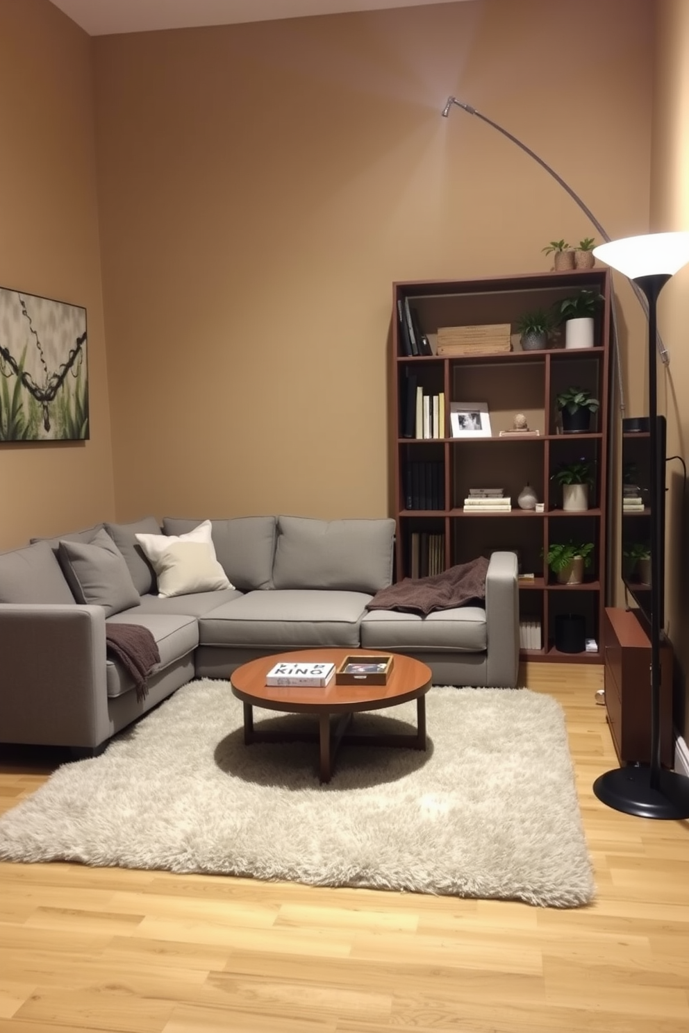 A cozy small living room featuring a corner sofa upholstered in a soft gray fabric. The walls are painted in a warm beige color, and a round coffee table sits in front of the sofa, adorned with a decorative tray and a few books. In the corner opposite the sofa, a tall bookshelf filled with plants and decorative items adds character to the space. A plush area rug anchors the seating area, while a floor lamp with a sleek design provides warm lighting for a welcoming atmosphere.