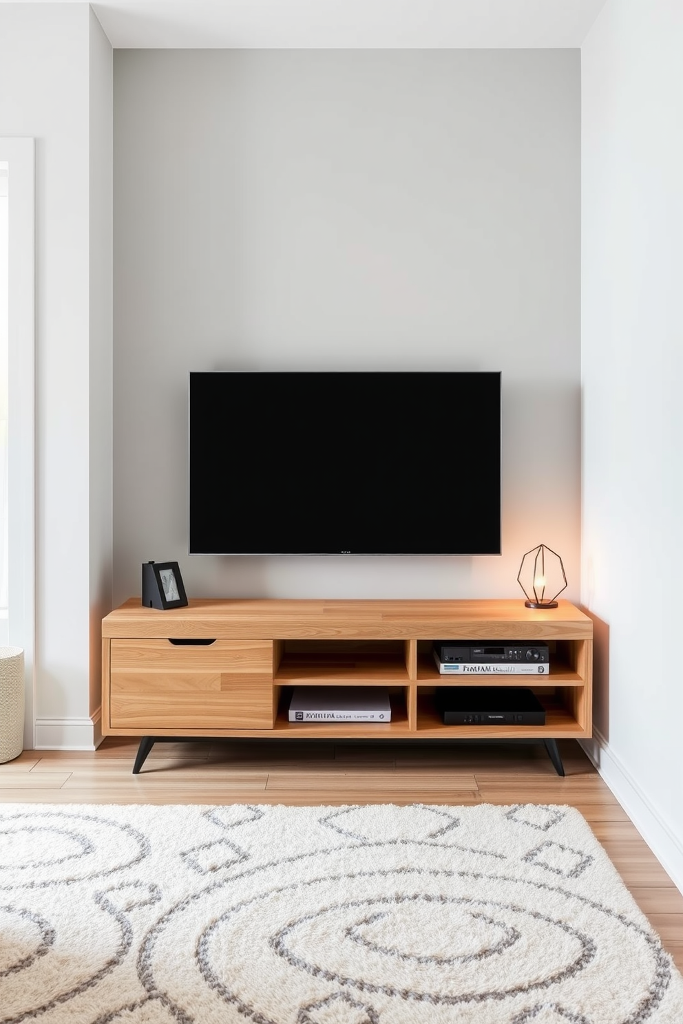 A modern small living room featuring a slim media console designed for a TV. The console is finished in a light wood with sleek lines, positioned against a soft gray wall, complemented by a cozy area rug underneath.