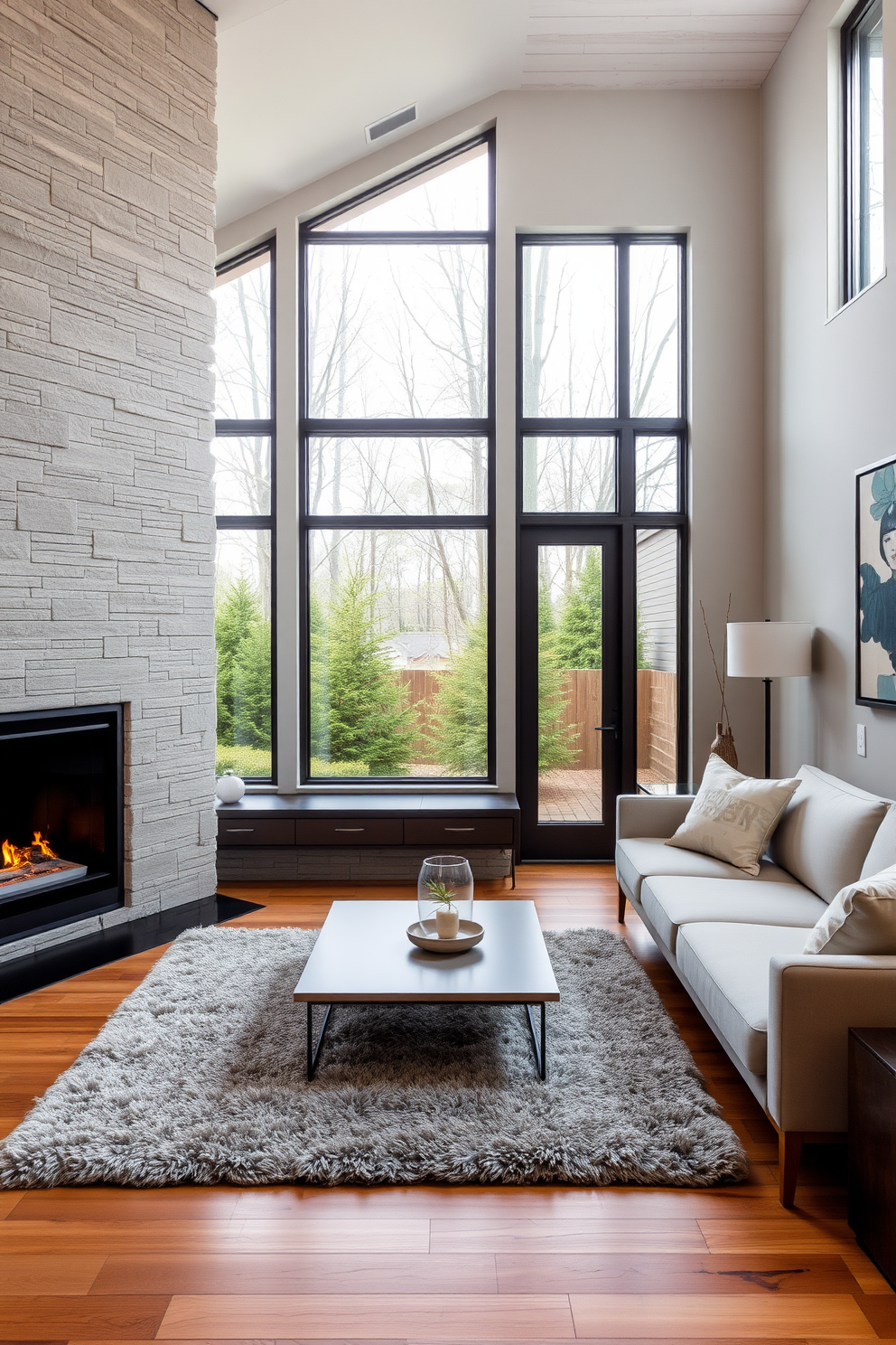 A cozy living room featuring a modern fireplace with a sleek stone surround. The space is adorned with a plush area rug and a stylish sectional sofa that invites relaxation. Large windows allow natural light to flood the room, highlighting the warm tones of the wooden flooring. A minimalist coffee table sits in front of the sofa, complemented by contemporary art on the walls.