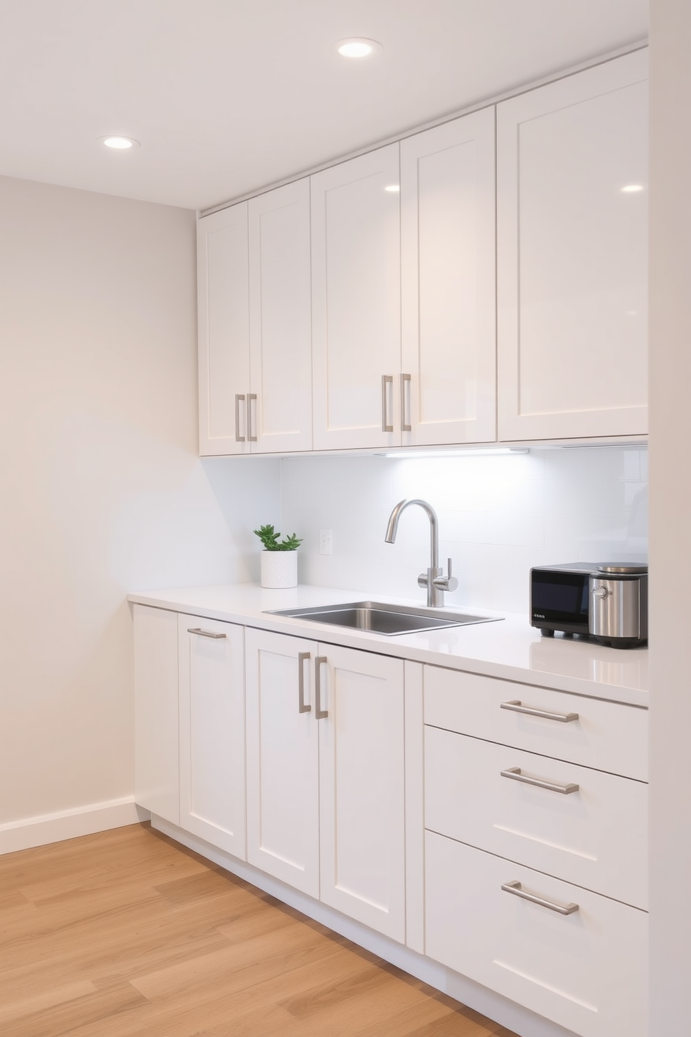 A small office kitchen featuring soft close cabinets that provide quiet functionality. The cabinetry is finished in a sleek white with brushed nickel handles, complementing the minimalist aesthetic of the space.