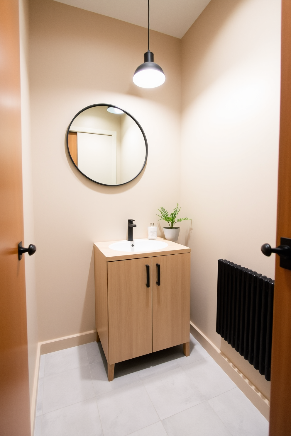 A serene small powder room featuring a neutral color palette that promotes tranquility. The walls are painted in a soft beige, complemented by a light wood vanity with a simple white sink. A round mirror with a thin black frame hangs above the vanity, reflecting the gentle light from a small pendant fixture. The floor is adorned with light gray tiles, and a small potted plant adds a touch of greenery to the space.