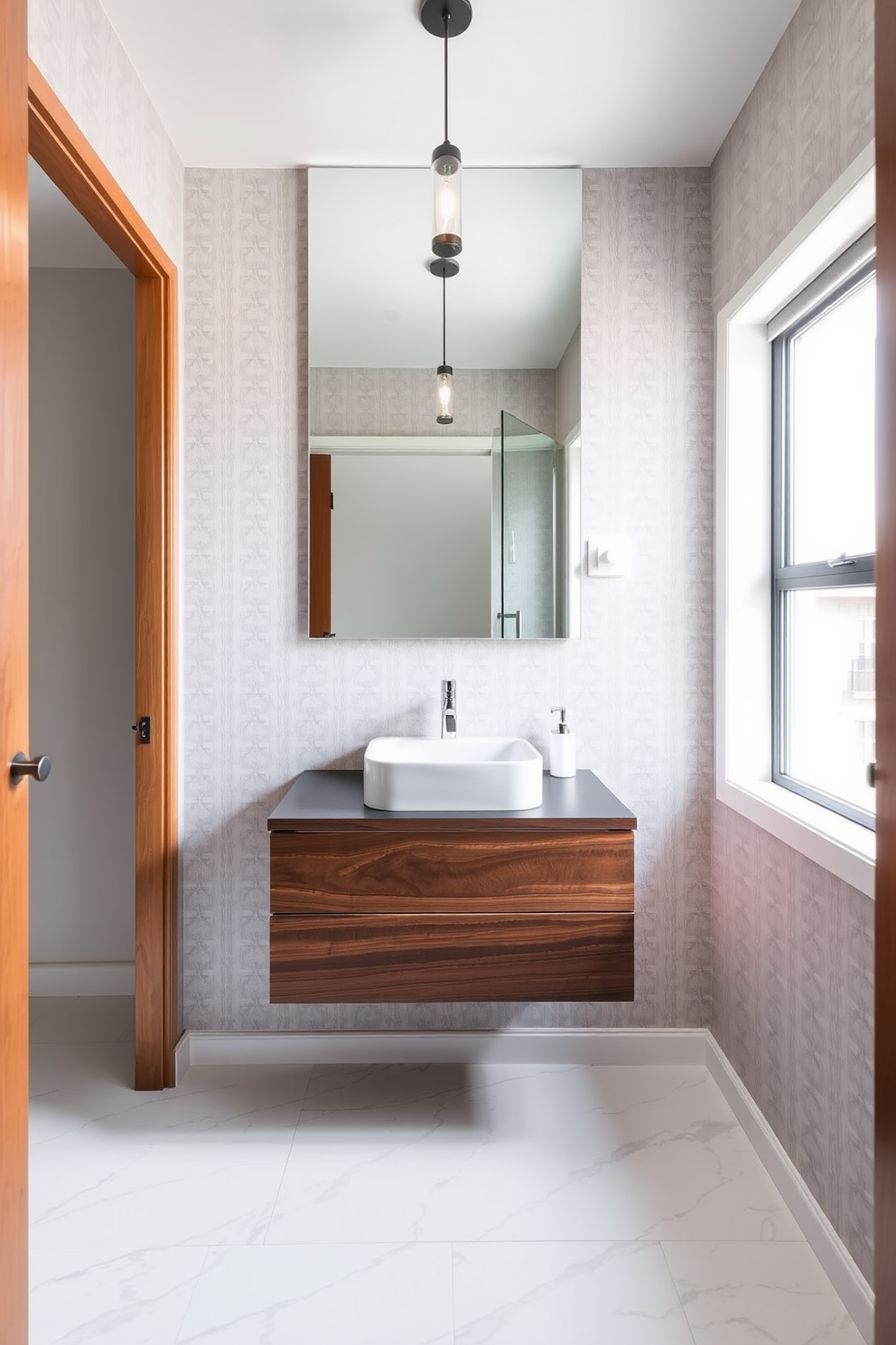 A floating vanity made of rich walnut wood is the centerpiece of the small powder room, featuring a sleek white sink and a polished chrome faucet. The walls are adorned with soft gray wallpaper, creating an airy feel, while the floor is finished with large-format marble tiles for a touch of luxury. Above the vanity, a large frameless mirror reflects the natural light coming from a nearby window, enhancing the room's spaciousness. A minimalist pendant light hangs from the ceiling, providing warm illumination and adding to the modern elegance of the design.