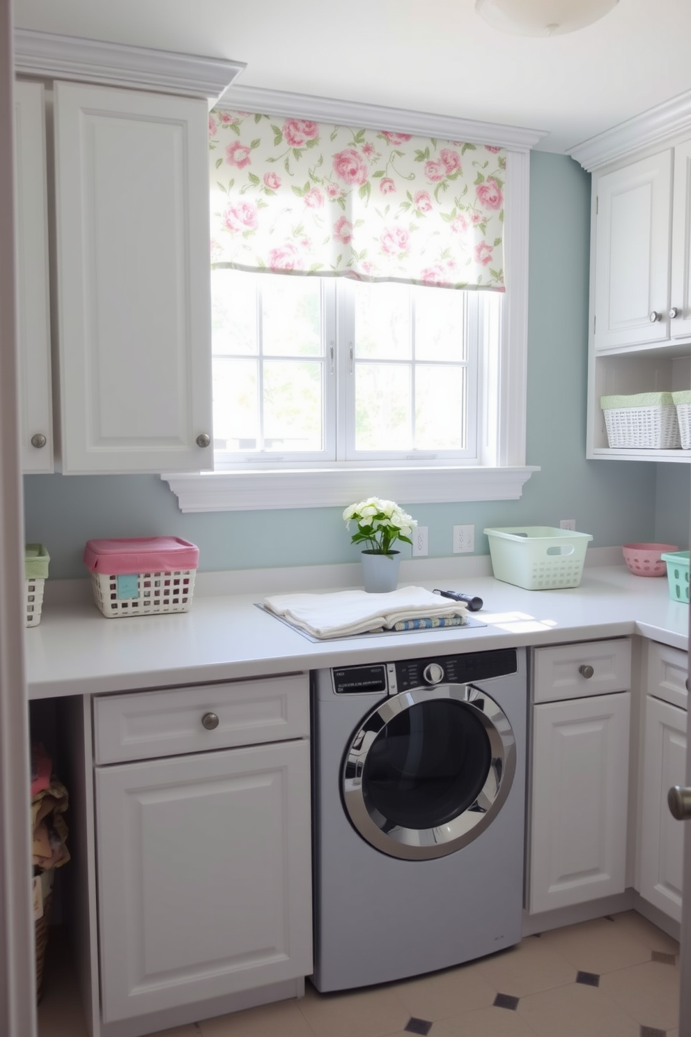 A bright and airy laundry room with white cabinetry and a cheerful window treatment featuring floral patterns. The space is adorned with pastel-colored baskets and a countertop for folding clothes, creating an inviting atmosphere.