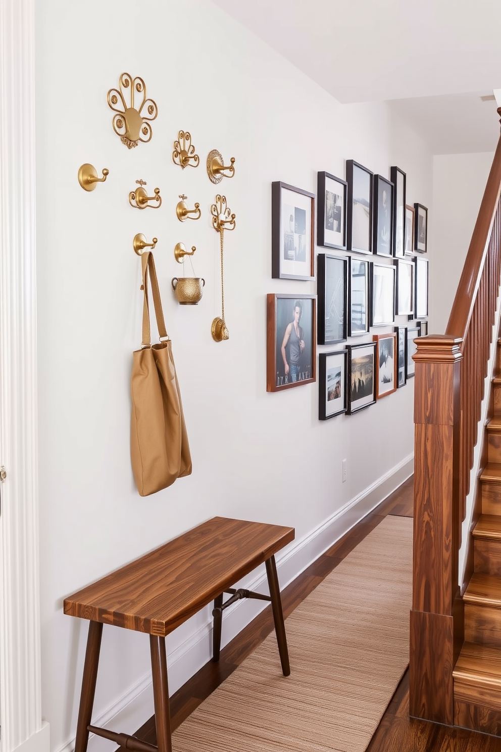 Stylish hooks for hanging accessories. The hooks are made of brushed brass and feature intricate designs, mounted on a soft white wall. They are arranged in a visually pleasing pattern, showcasing a mix of functional and decorative elements. Below, a small wooden bench with a plush cushion adds comfort and style to the entryway. Staircase wall design ideas. The wall along the staircase is adorned with a gallery of framed artwork in varying sizes, creating an eclectic and inviting atmosphere. Beneath the artwork, a sleek runner rug in muted tones complements the wooden staircase, adding warmth and texture to the space.